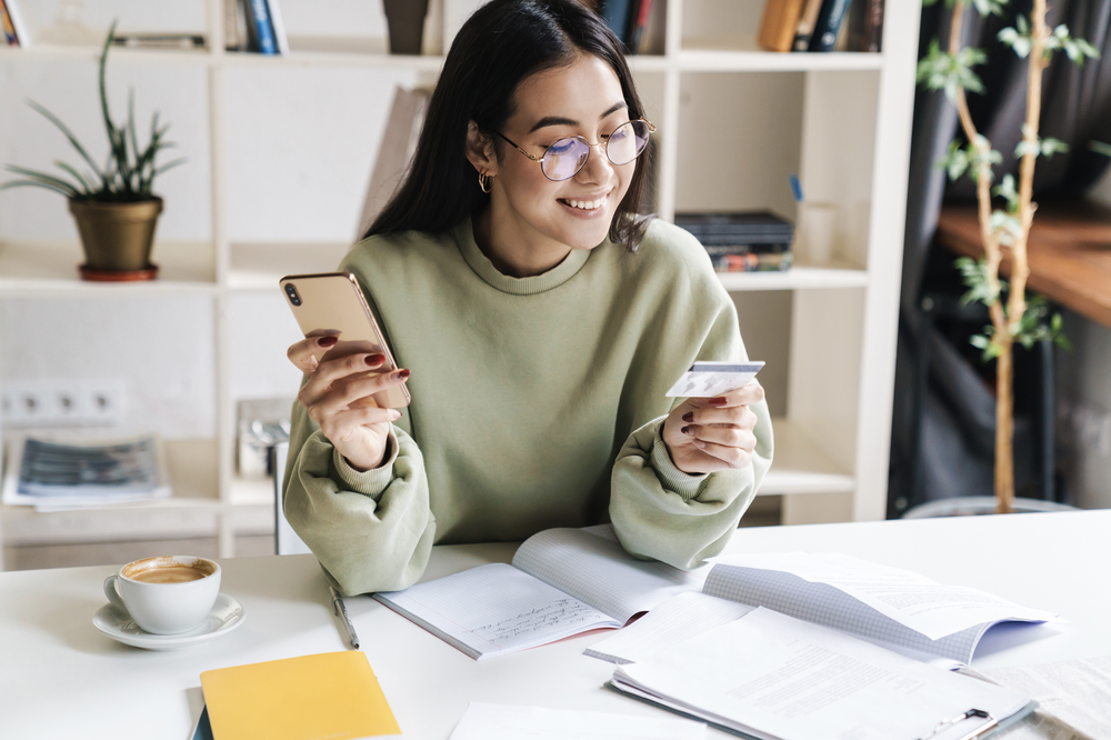 Member holding a credit card while applying on her phone