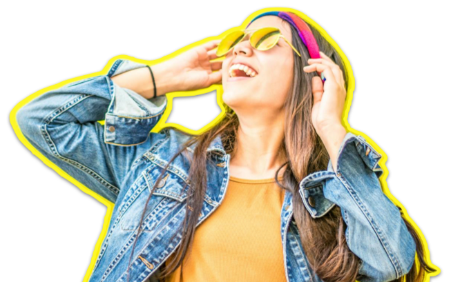 A young woman smiling and enjoying music with yellow sunglasses and headphones, wearing a denim jacket and orange shirt.