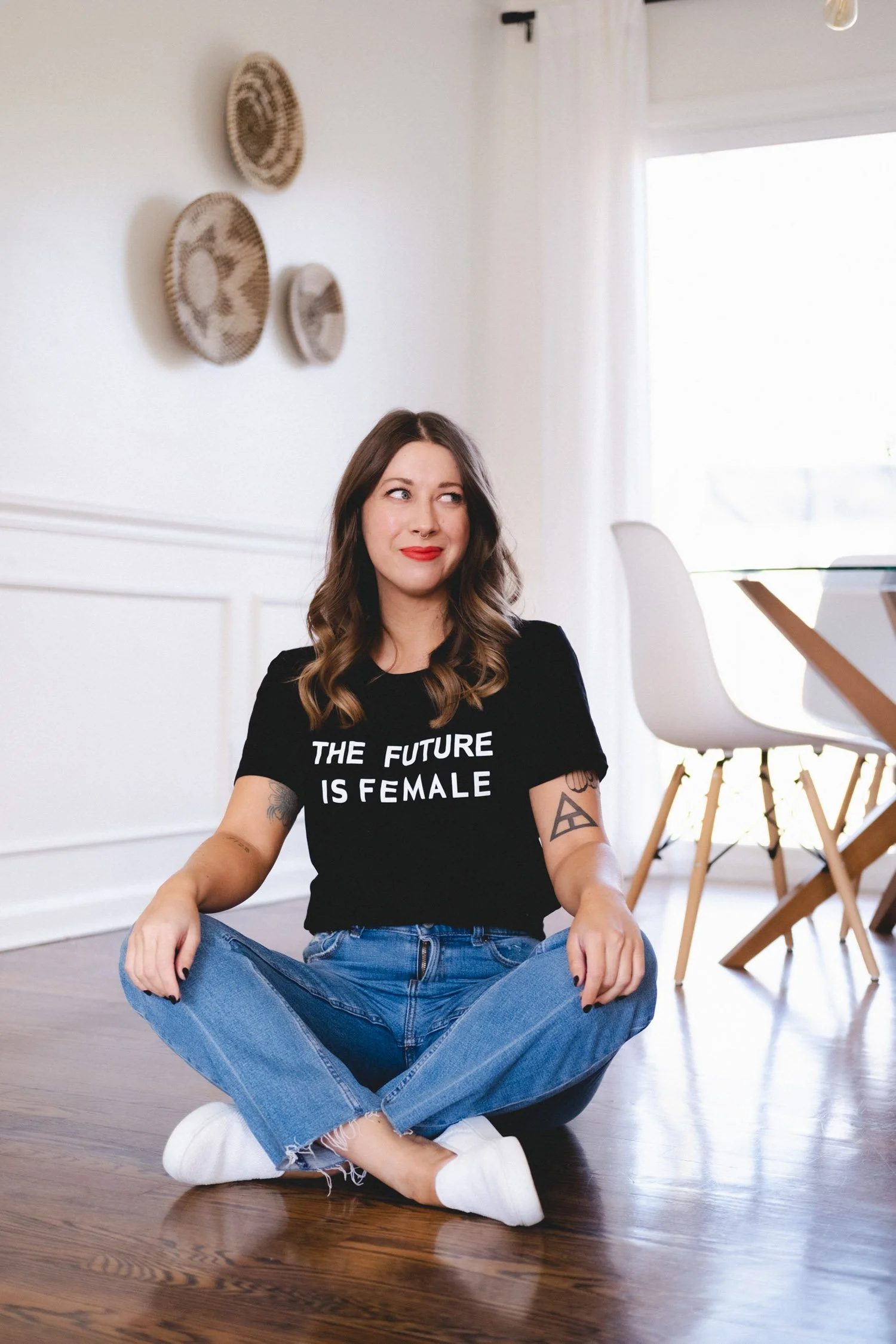 Woman sitting cross-legged on the floor, The Future is Female t-shirt, red lipstick, jeans