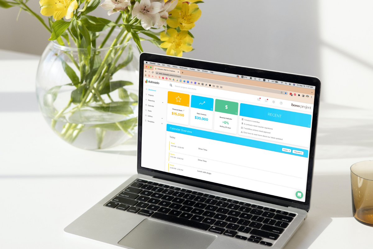 Dubsado dashboard on laptop, yellow flowers in vase