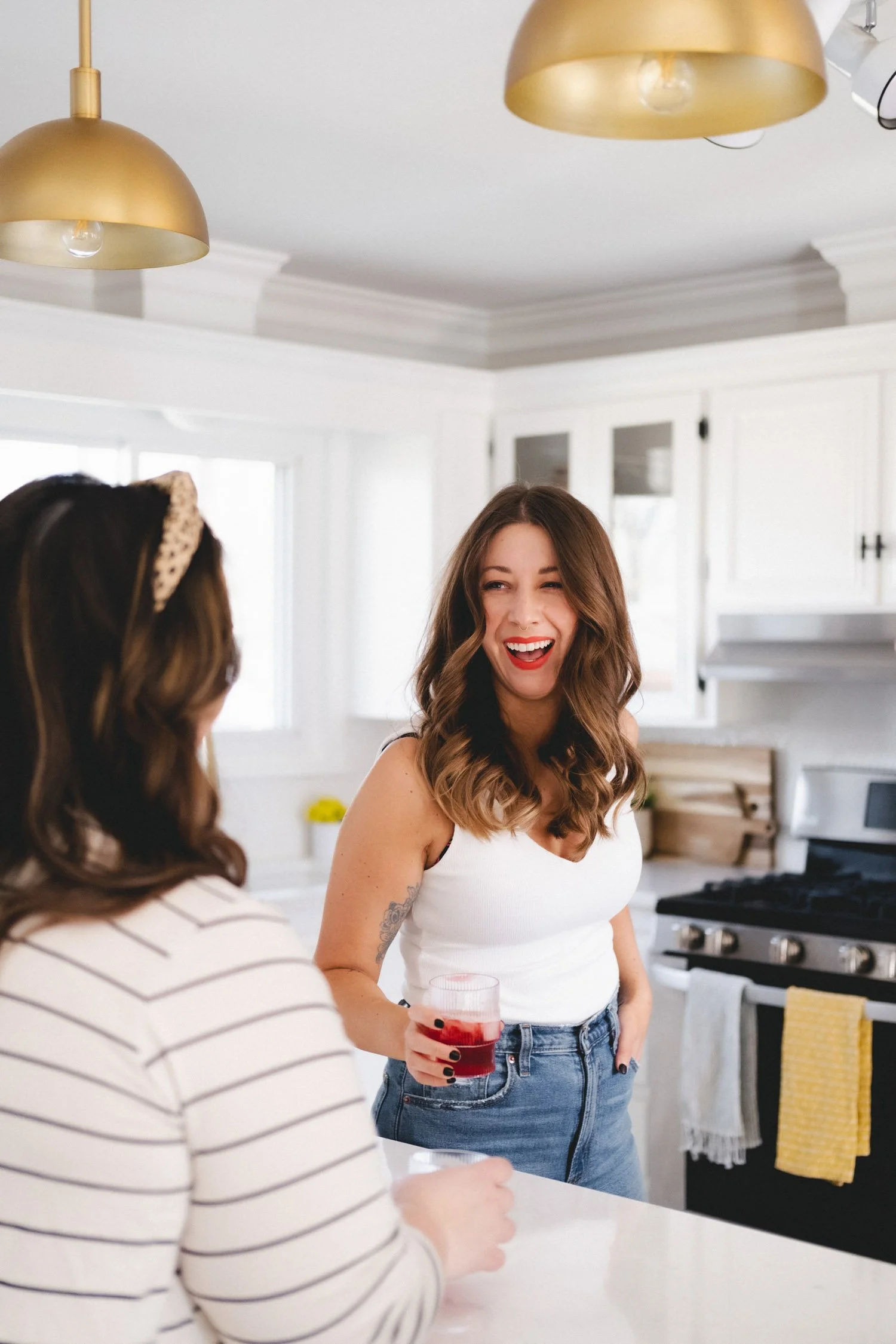 Woman laughing holding drink, kitchen