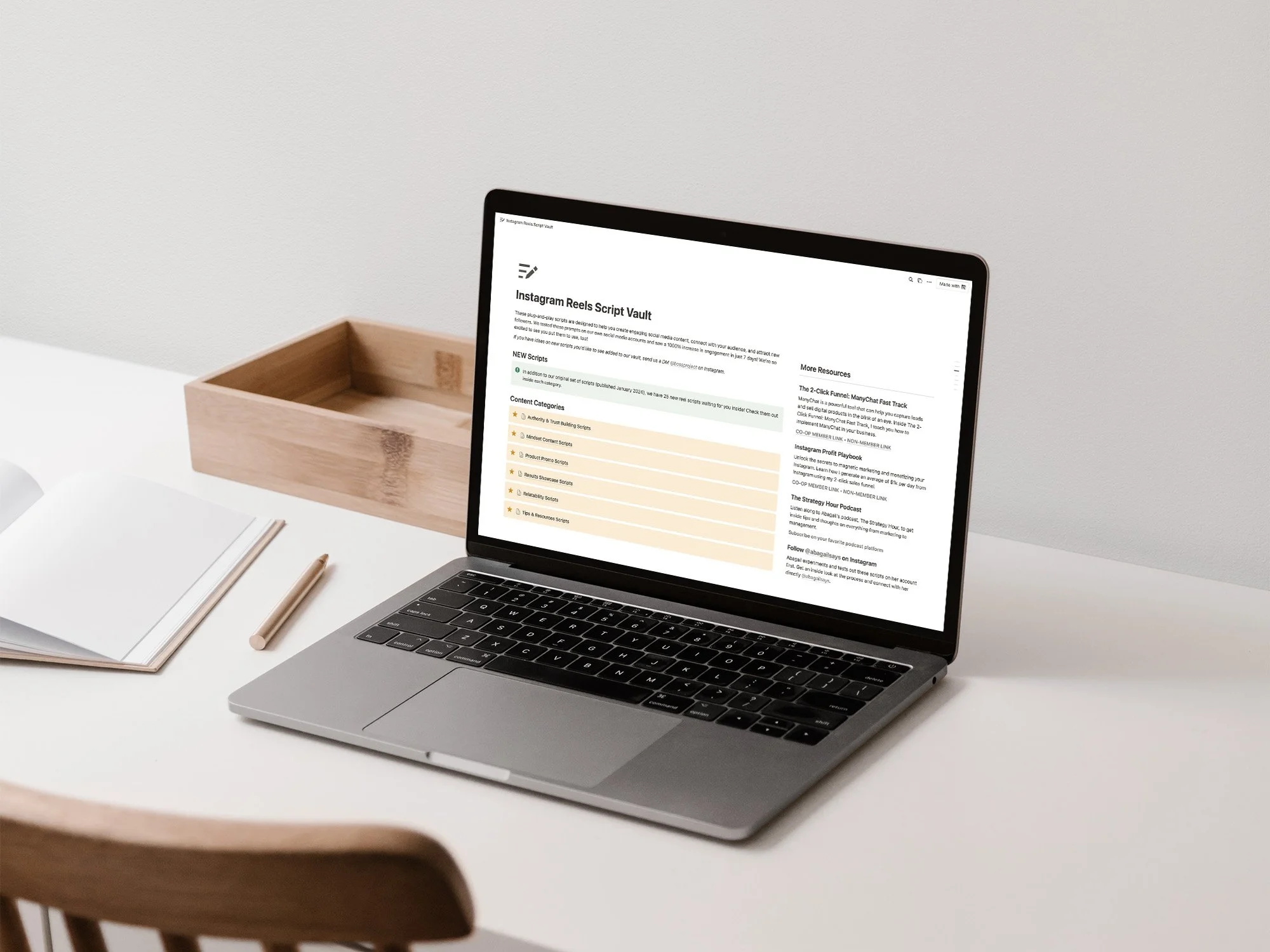 Notion script vault on laptop, sitting on desk with notebook and pen