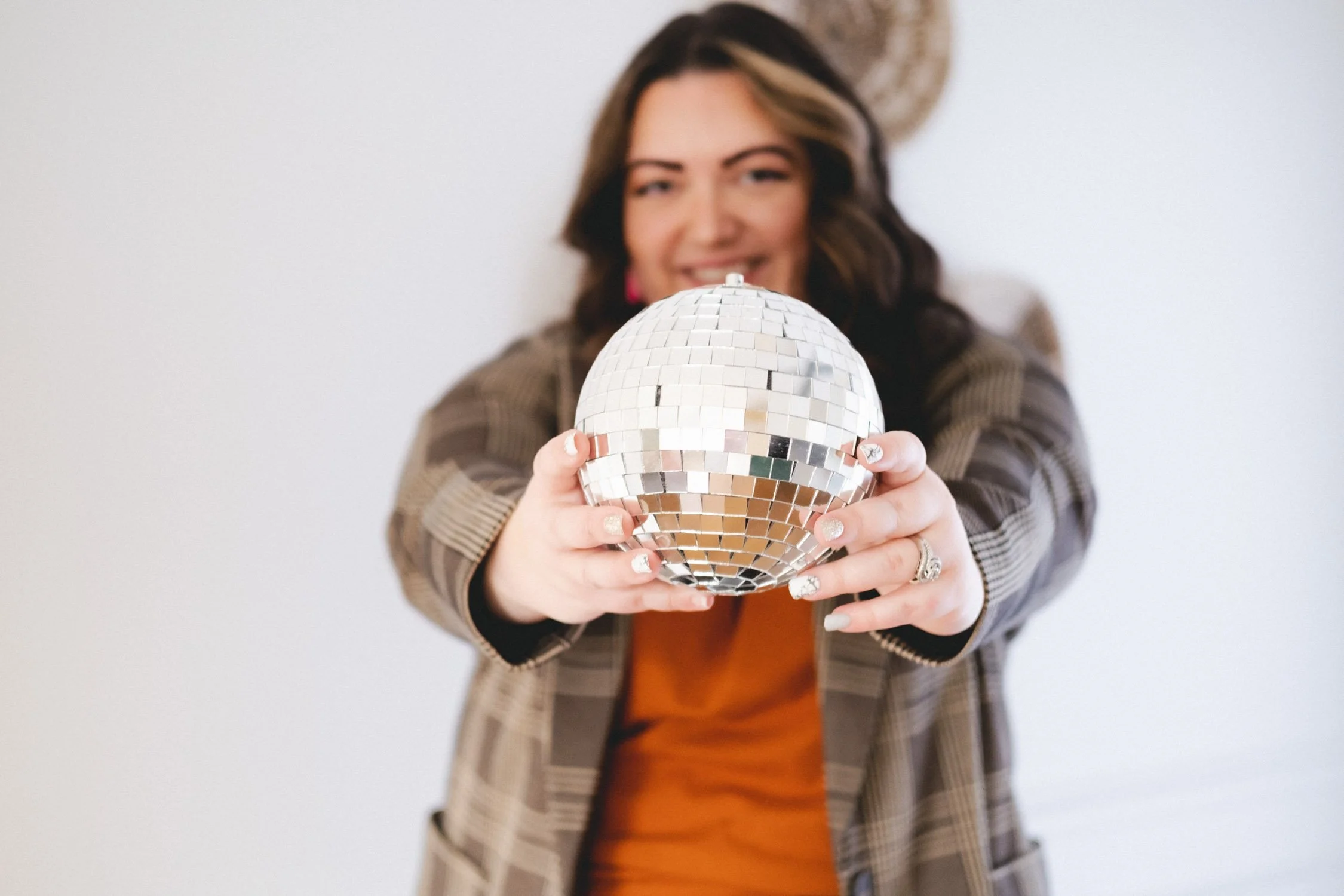 Woman holding disco ball, smiling