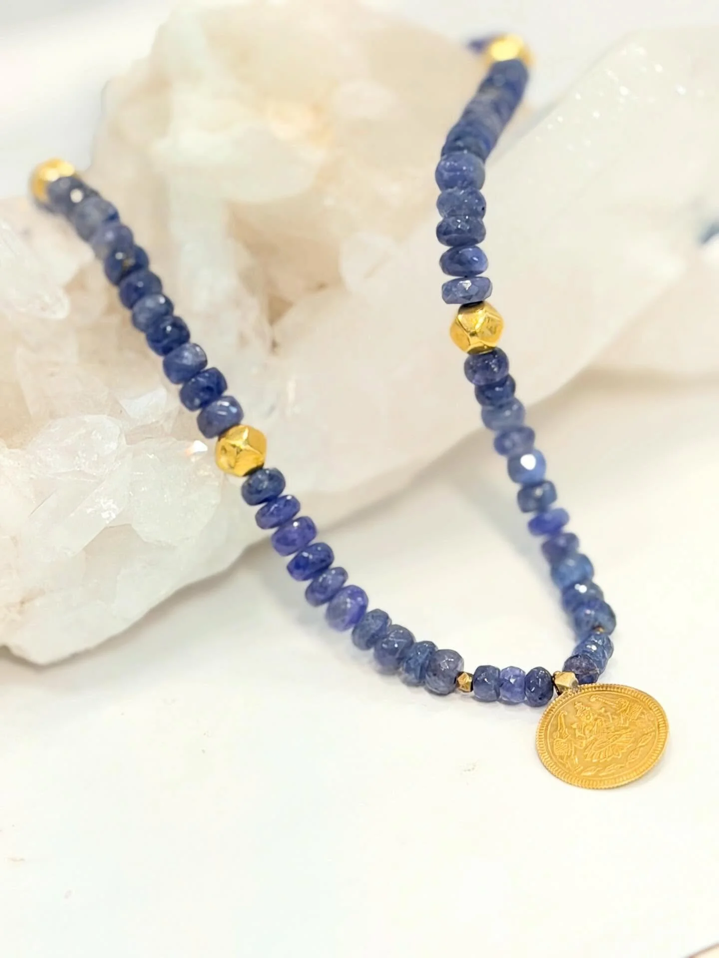 Blue Iolite 18k gold Lakshmi necklace. The Lakshmi coin is sourced in India and features beautiful elephants and lakshim sitting on her iconic lotus.  The coin itself is an exceptional work of art. Lakshmi is the Hindu  Divine feminine goddess of wea