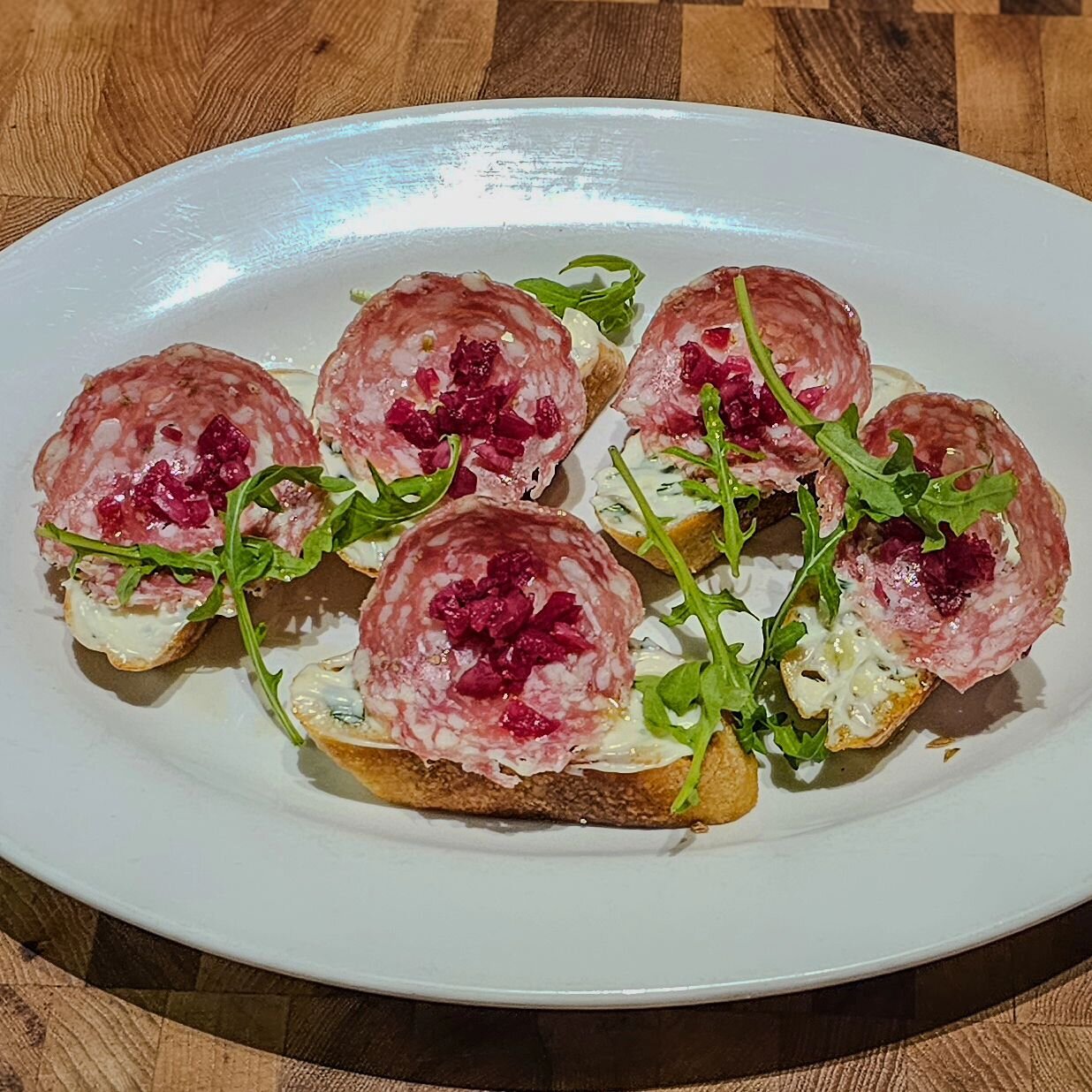 Lunch starts today at 11 am. 

Here, we have our featured appetizer, the crostini. Here we spread house made salsa ruccola over toast points, topped with salame, pickled onions, and then garnished with arugula. 

#crostini #salame #lunchtime #trueita