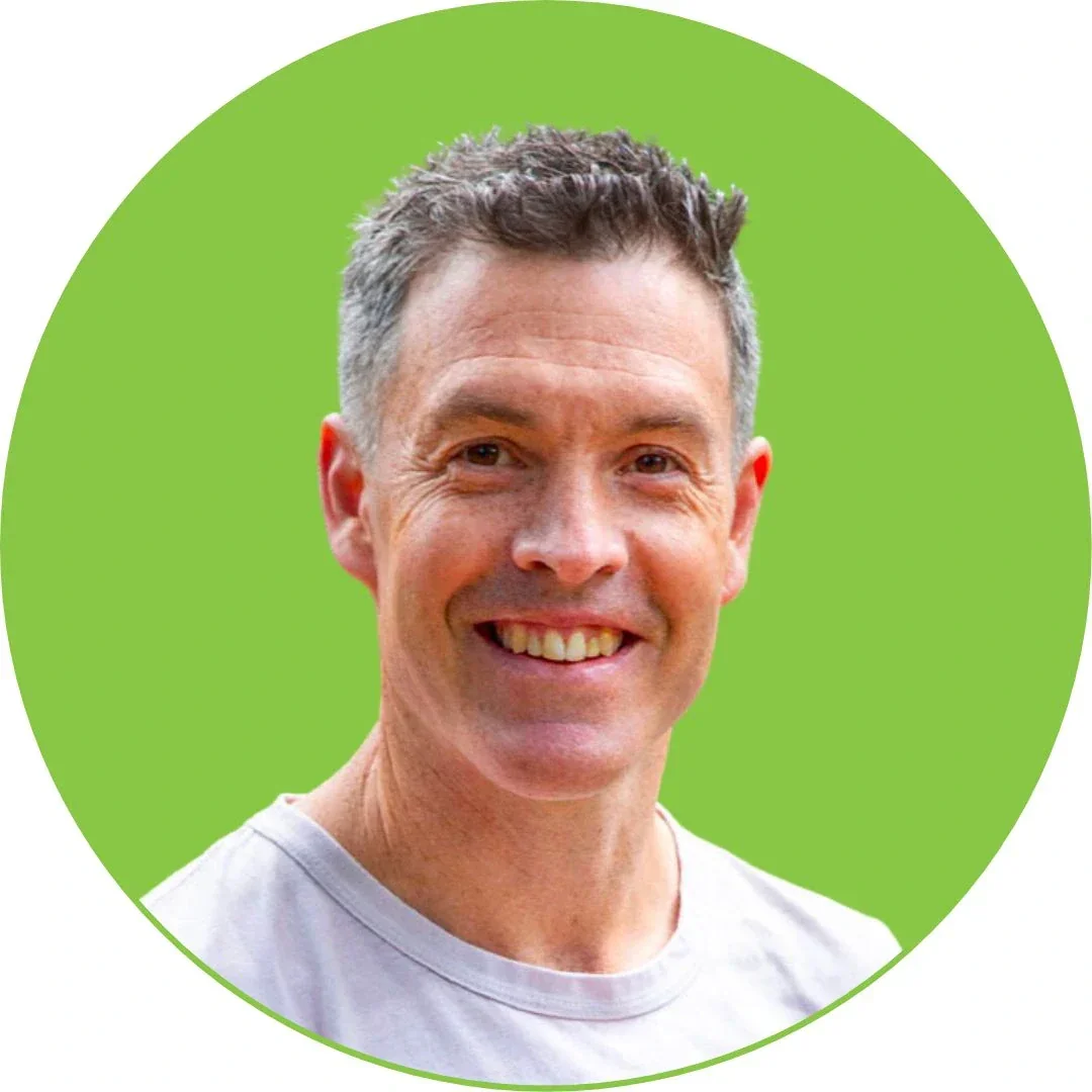 Headshot of a smiling middle-aged man with short gray hair, wearing a light-colored shirt, against a bright green circular background.