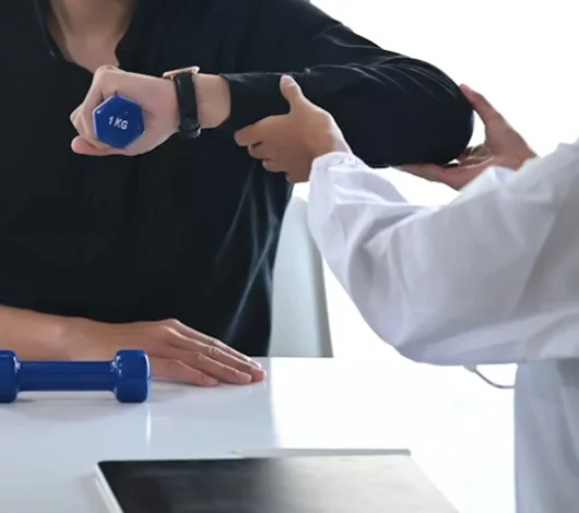 Chiropractor assessing shoulder and arm strength during injury rehab