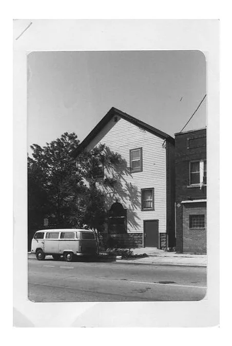 The exterior of Marquette Hotel with open windows revealing indoor dining area and green plants outside.