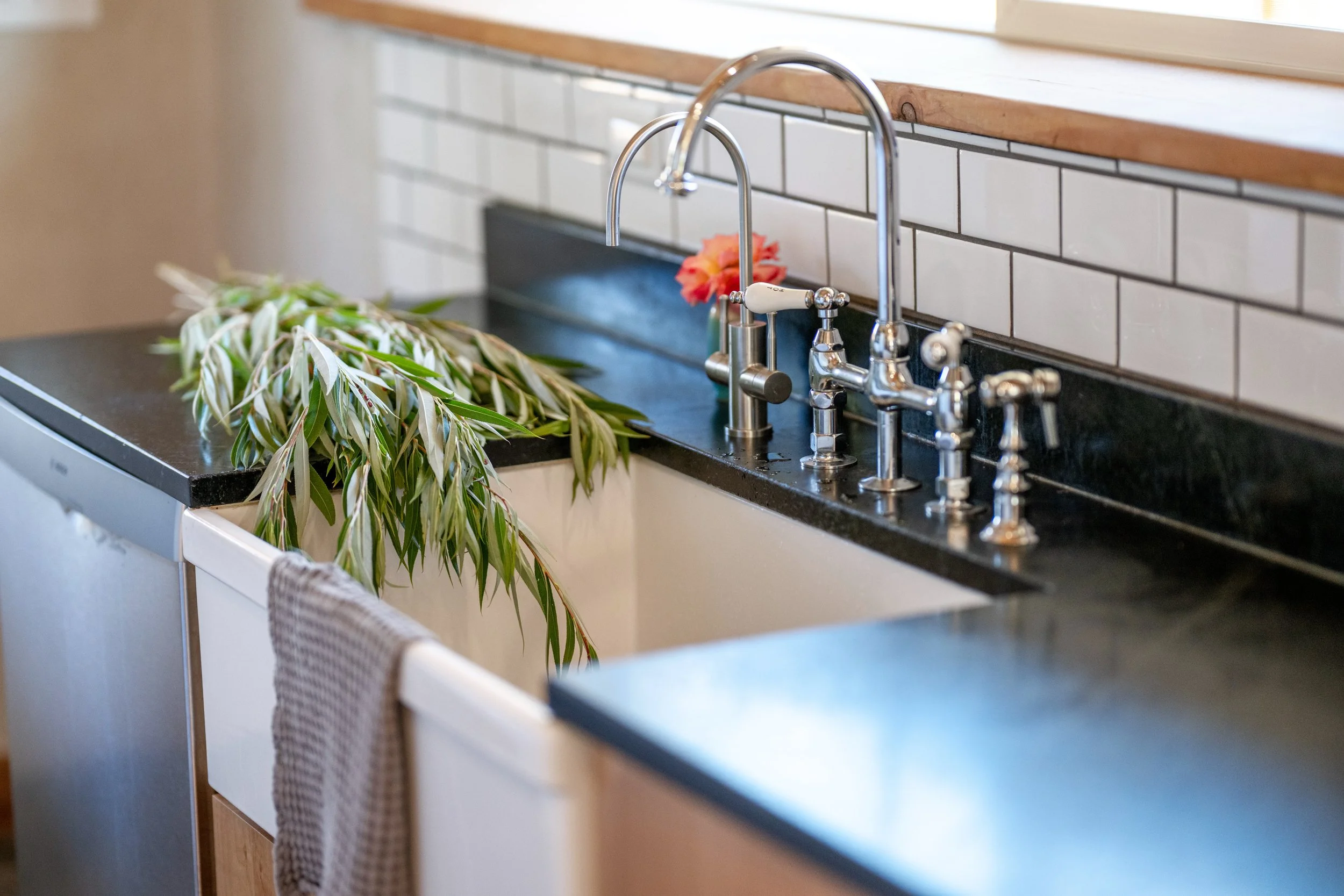 Freshly cut willow rests beside the farmhouse sink in the handcrafted kitchen at Be Easy Farm in Sequim, Washington.