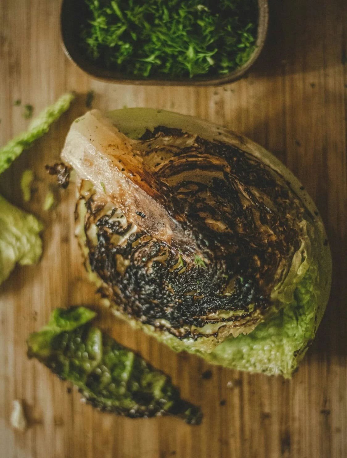 A charred wedge of cabbage on a wooden prep surface