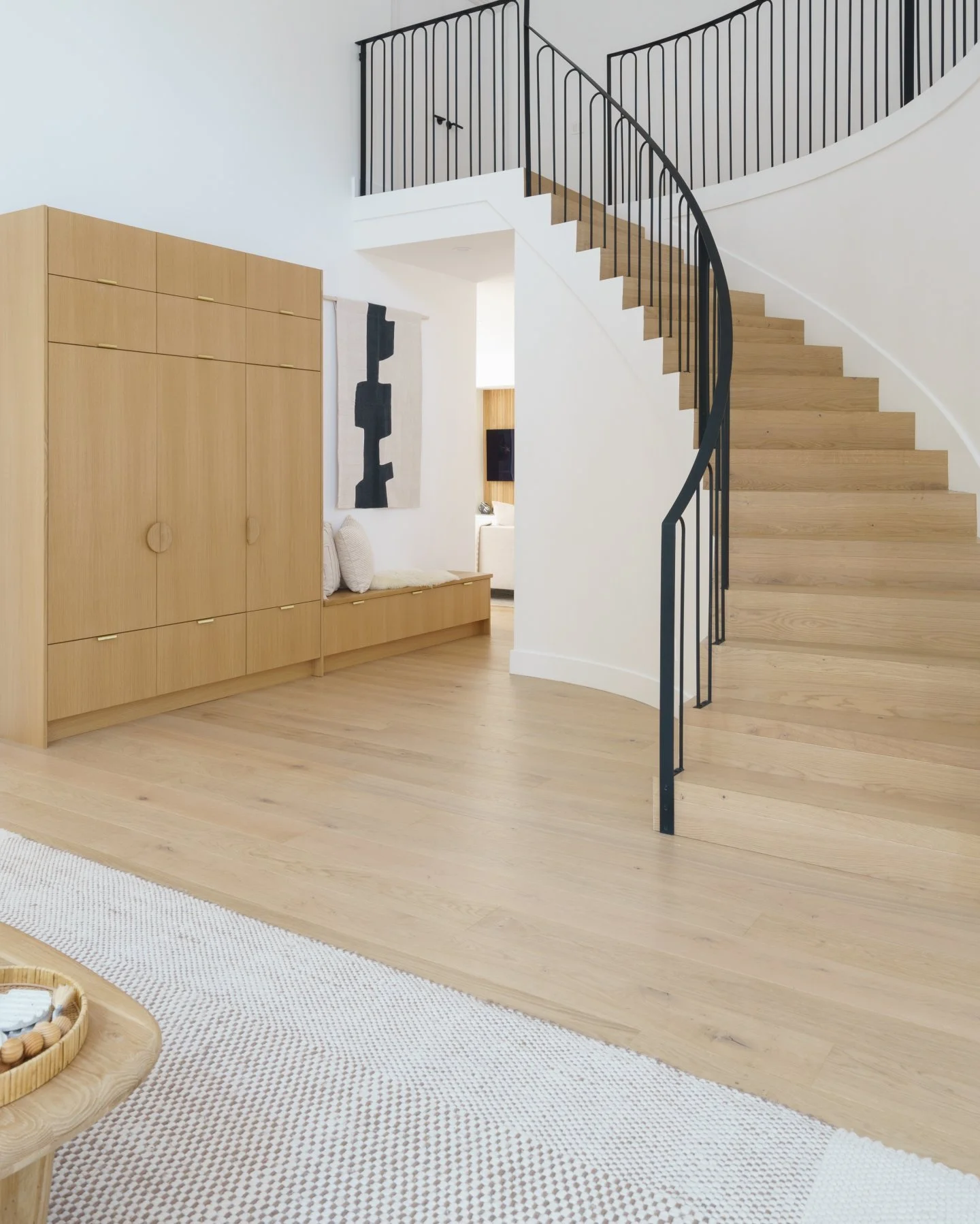 A bright, beautiful foyer with a curved staircase and light brown Stuga floors.