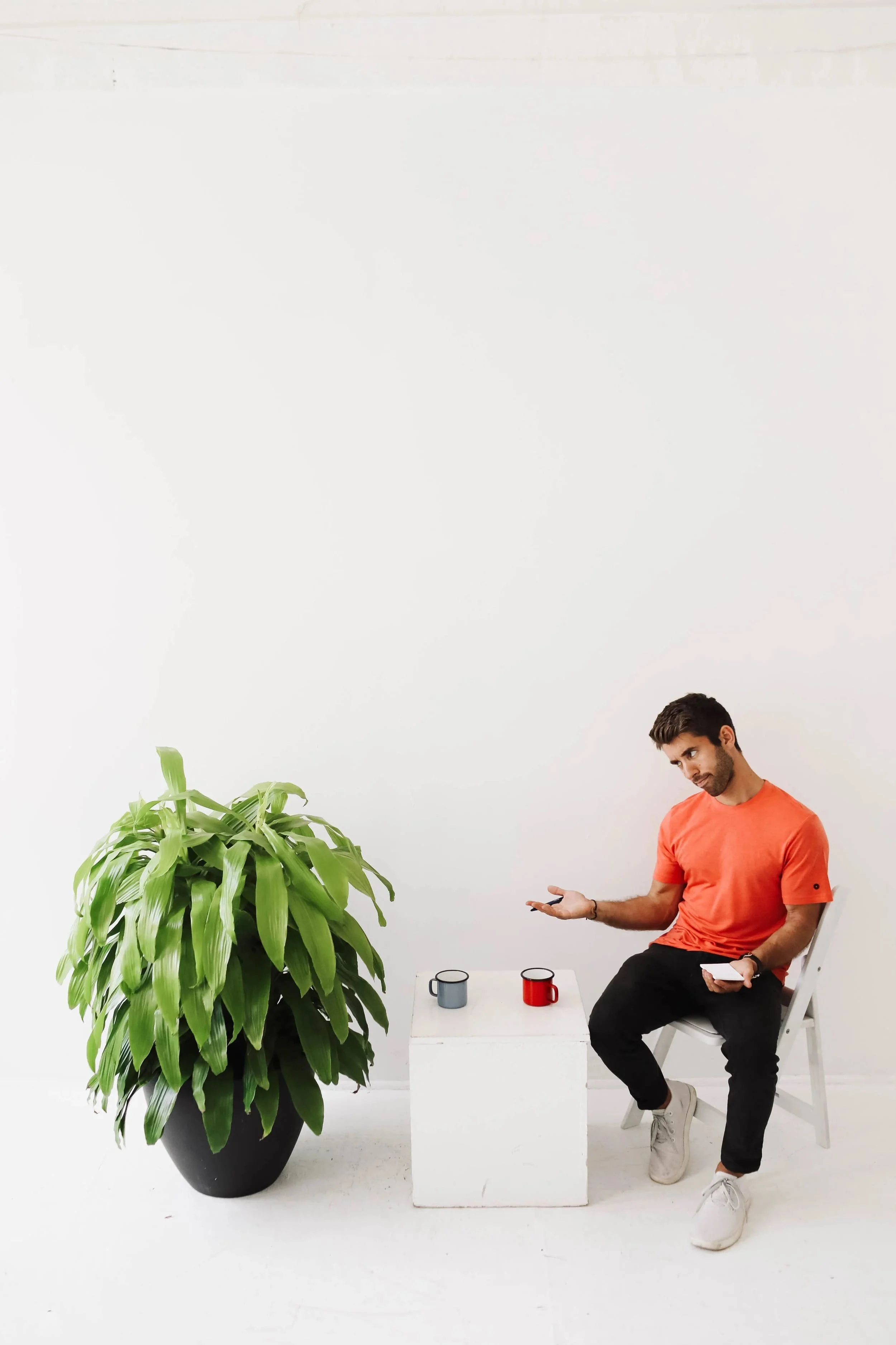 Farmer Nick sits at a table across from a large, green plant