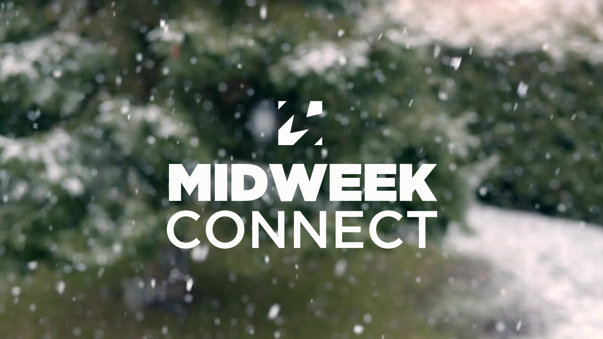 A group of people attending a classroom seminar or workshop with a presenter at the front, a large screen, and colorful posters on the wall.