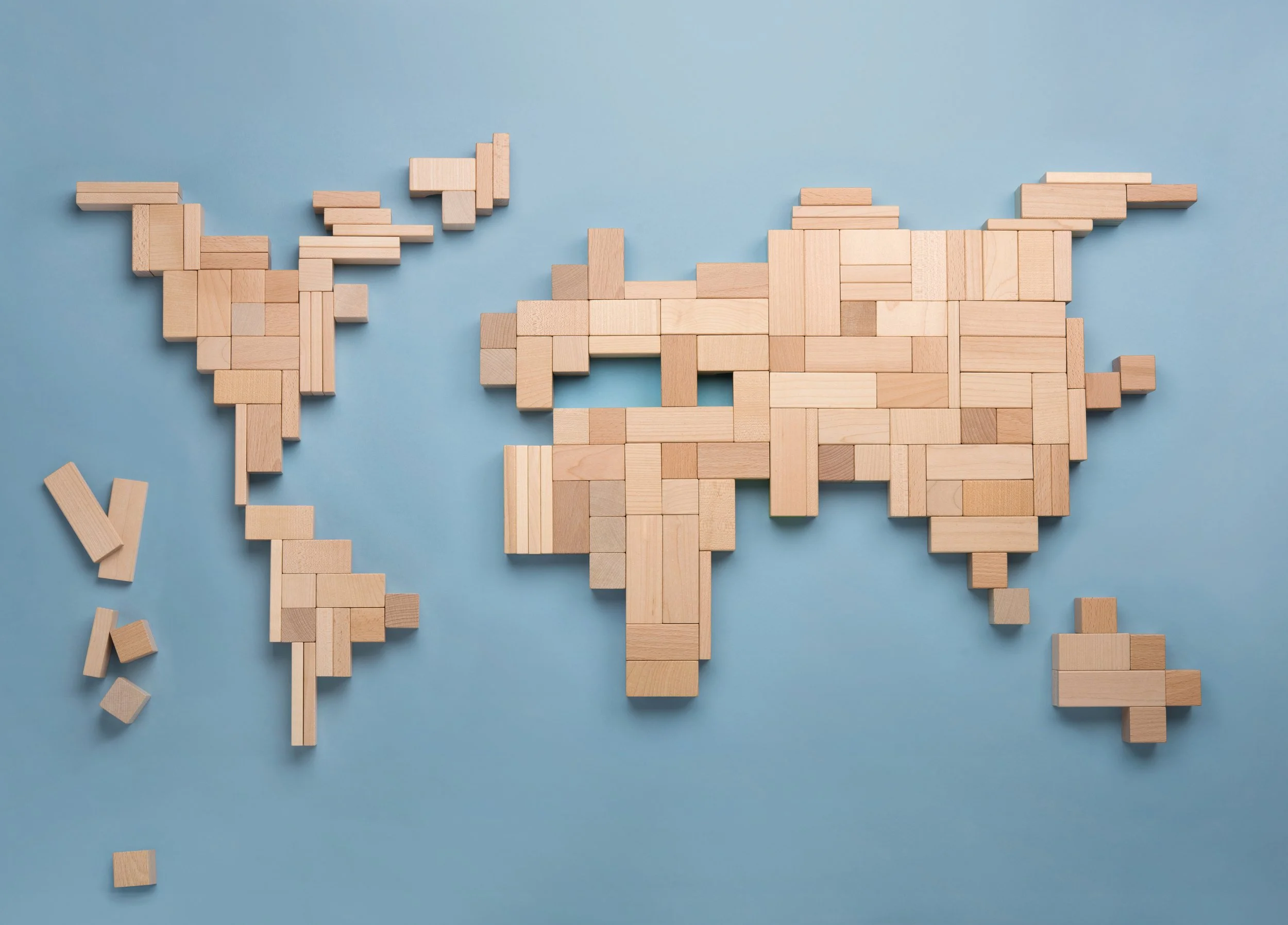 World map made of wooden blocks on a blue background.