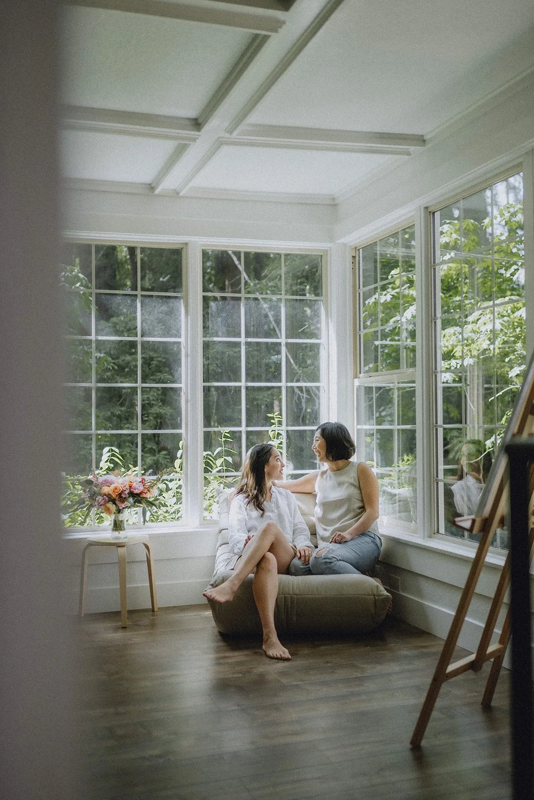 Couple sitting on a chair together with bright windows behind them