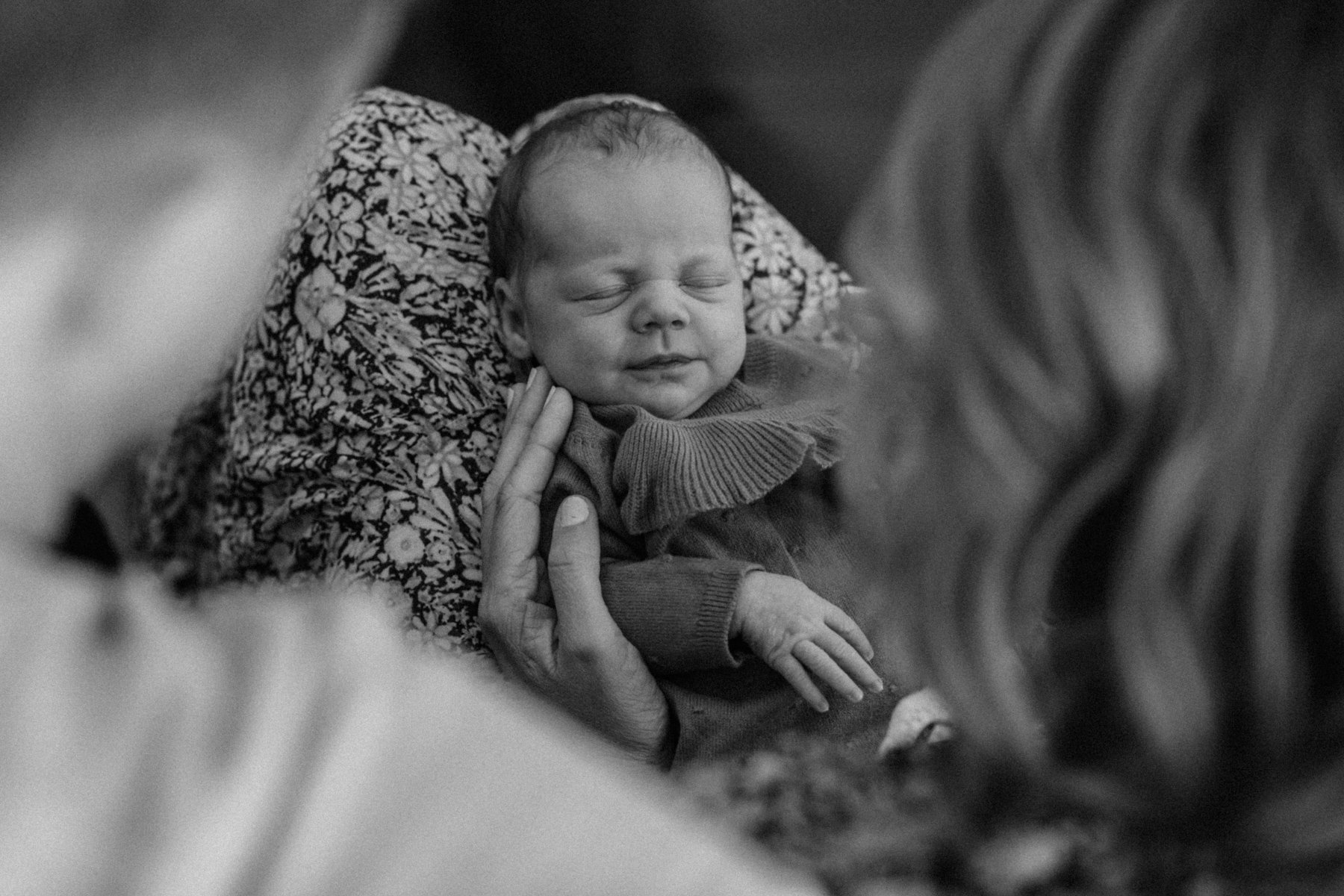 Black and white photo of sleeping newborn baby in parent's hands