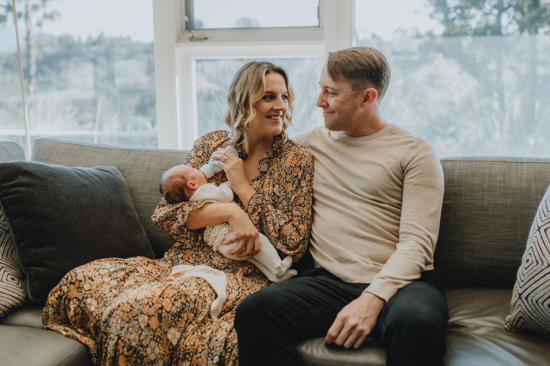 Mother feeding newborn a bottle while sitting next to father