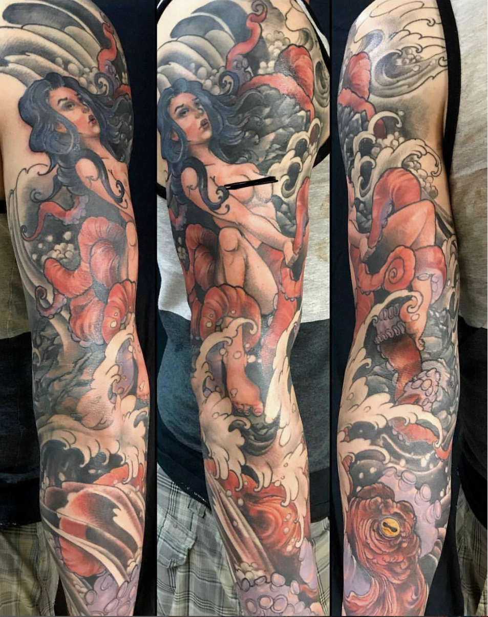 Tattoo sleeve featuring a woman with flowing hair surrounded by waves, clouds, and a creature resembling a dragon or octopus, with vivid colors and detailed shading.
