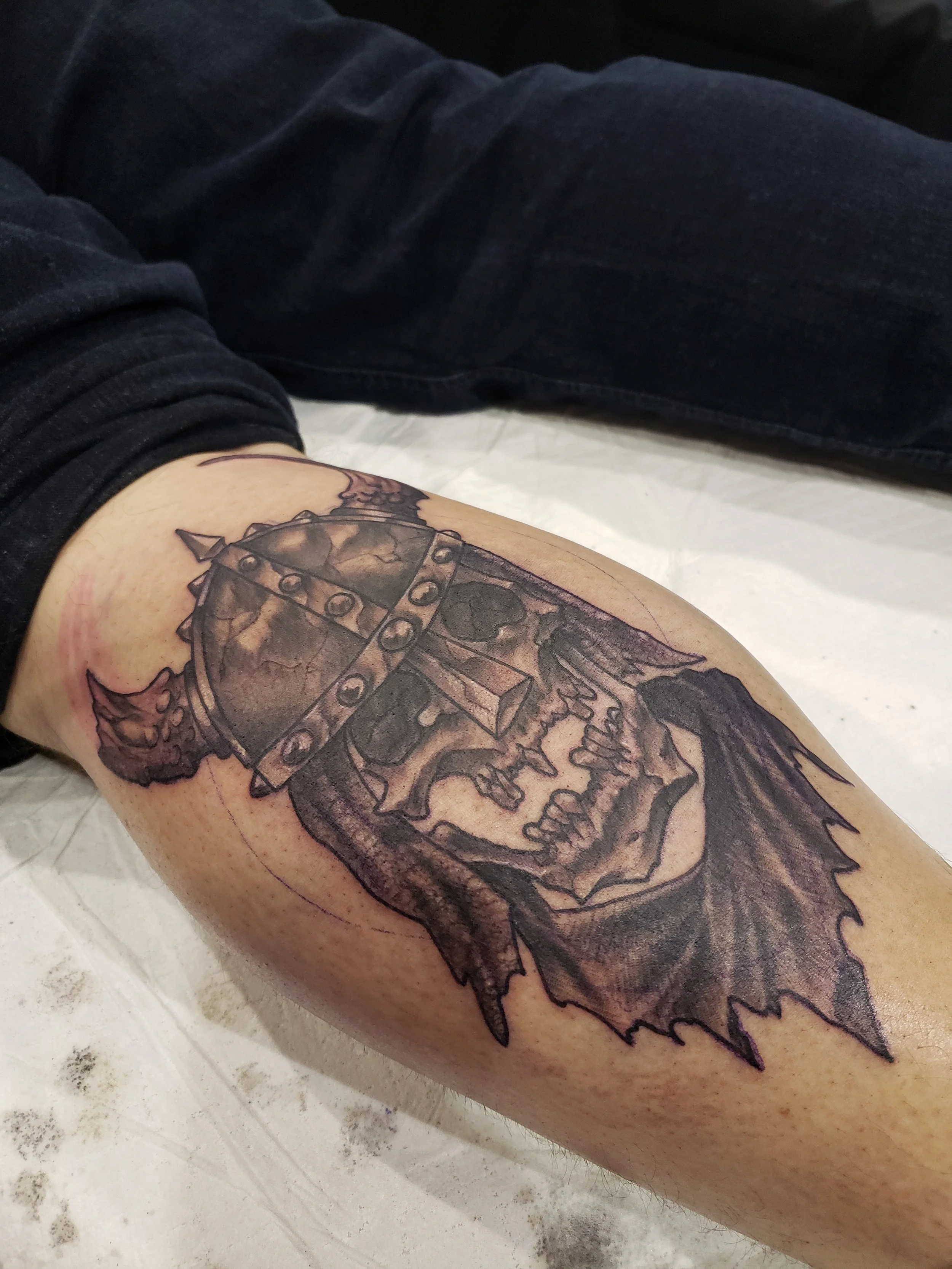 A tattoo of a Viking helmet with horns and detailed shading on a person's upper arm.