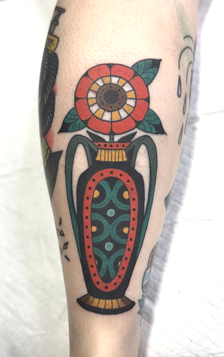 Tattoo of a colorful flower in a vase on a person's arm