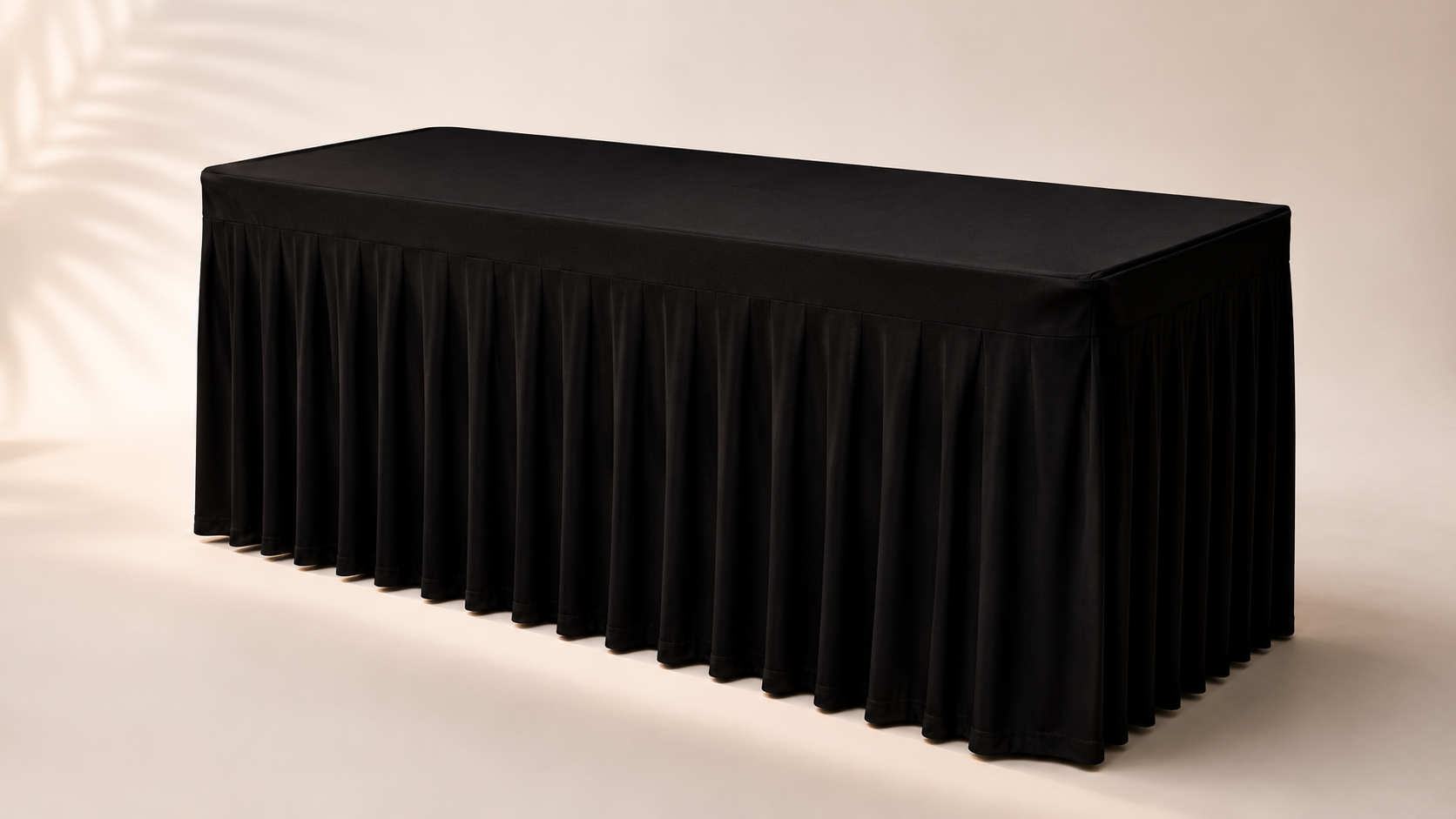 Black table with pleated skirt cover in a neutral setting.