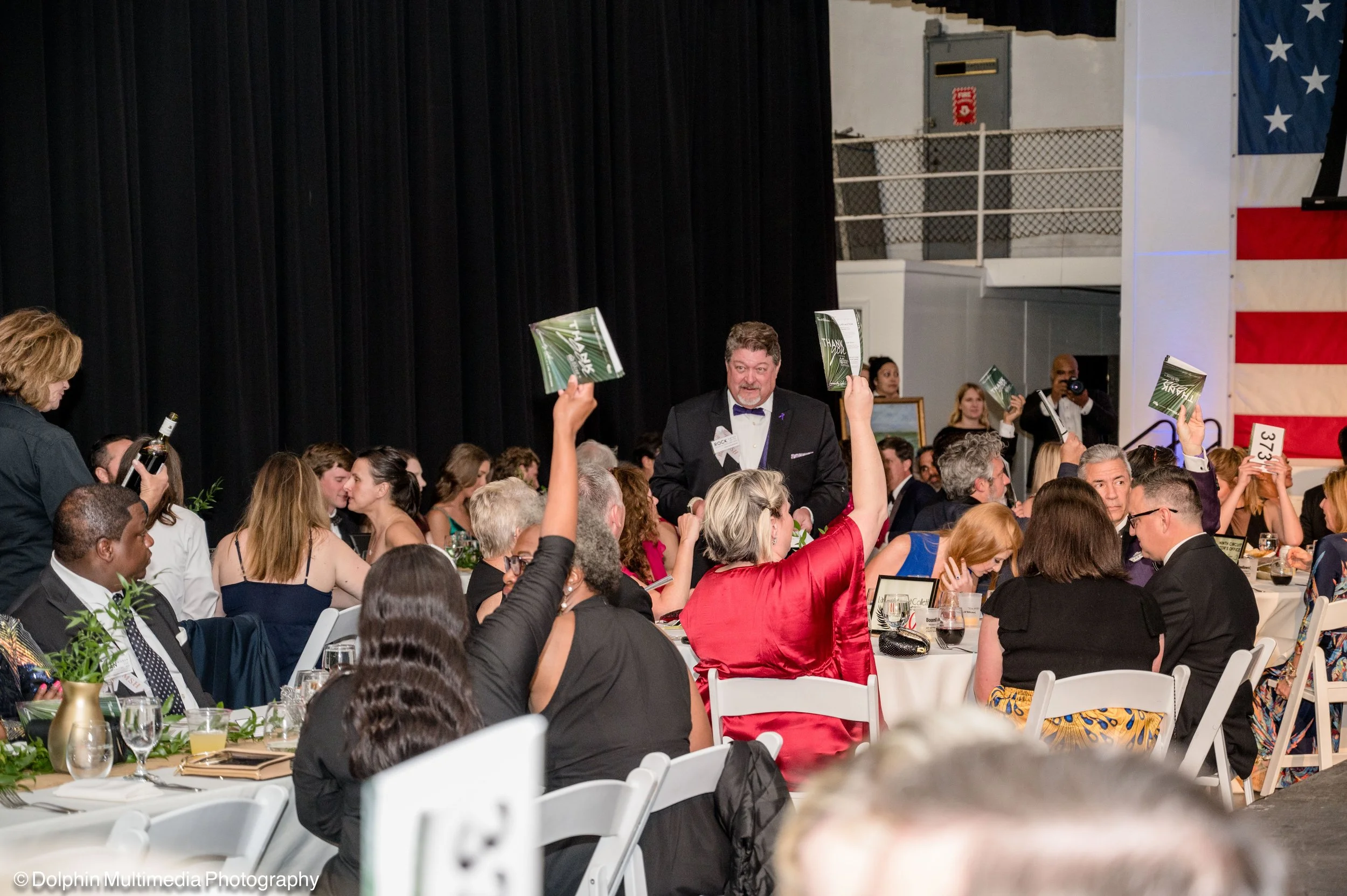 people raising their hands at a live auction