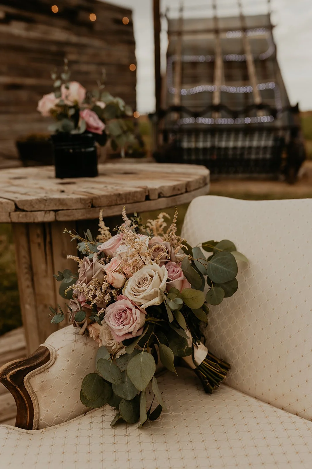 Bouquet of flowers on a vintage chair with rustic table and barn backdrop.