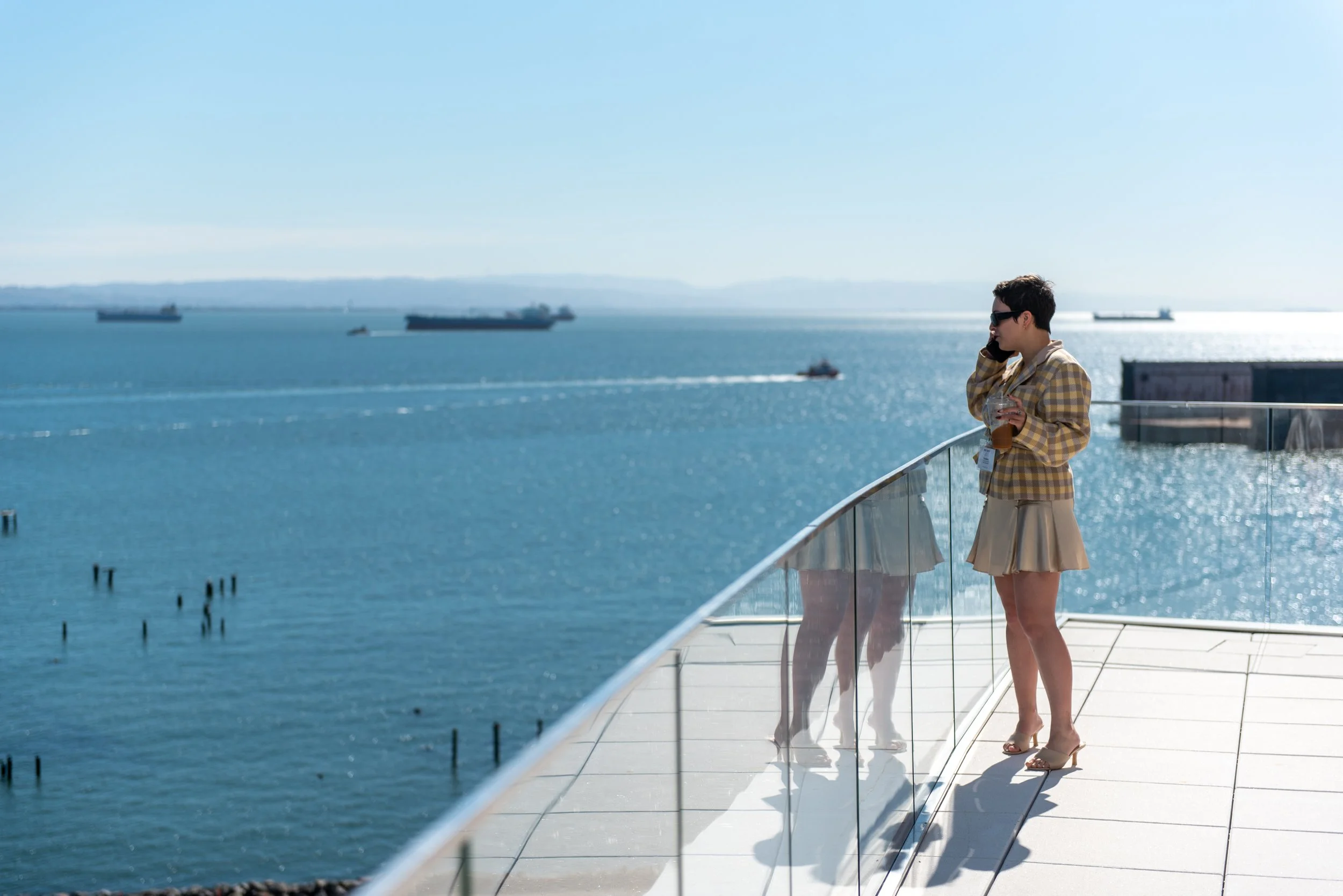 Madeline Raithel on the phone standing on the Chase Center Skybar balcony overlooking the San Francisco bay.