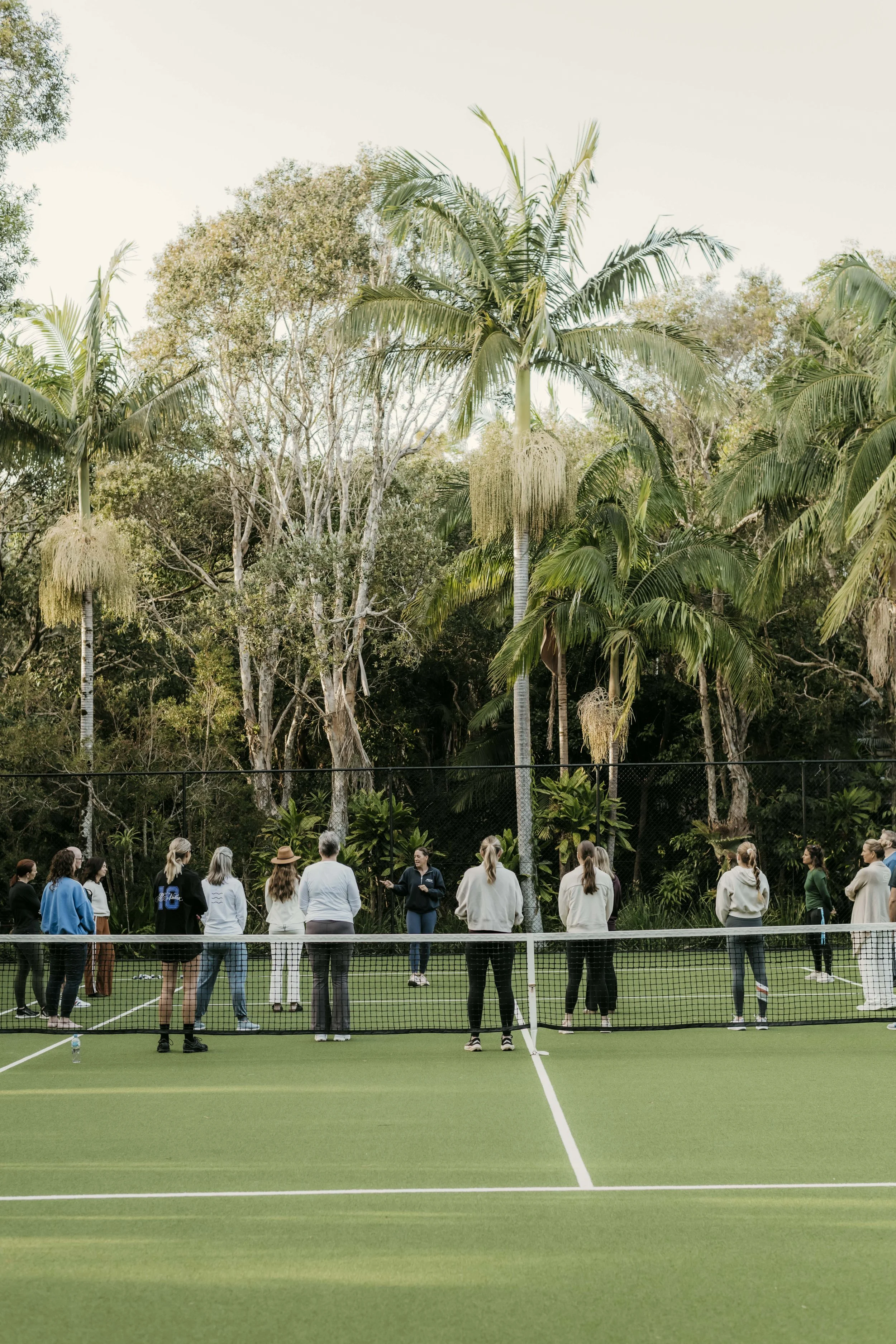 a group of people gathered on a tennis court to do a fitness class