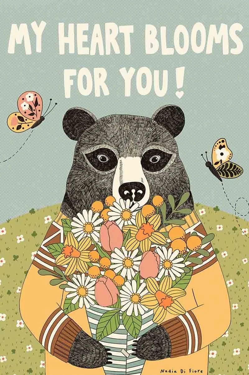Contemporary folk illustration of a bear holding a flower bouquet with "My Heart Blooms for You!" hand-lettering. A botanical greeting card by Nadia Di Fiore.