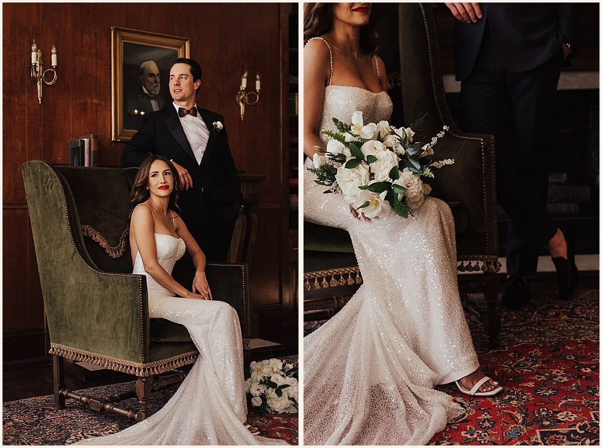 A bride and groom in a luxurious, wood-paneled room with antique furniture. The bride is seated in a green velvet chair, wearing a sparkly white wedding dress and holding a white bouquet. The groom, standing behind her, is dressed in a black tuxedo with a bowtie. The room features a framed portrait on the wall and a patterned rug.