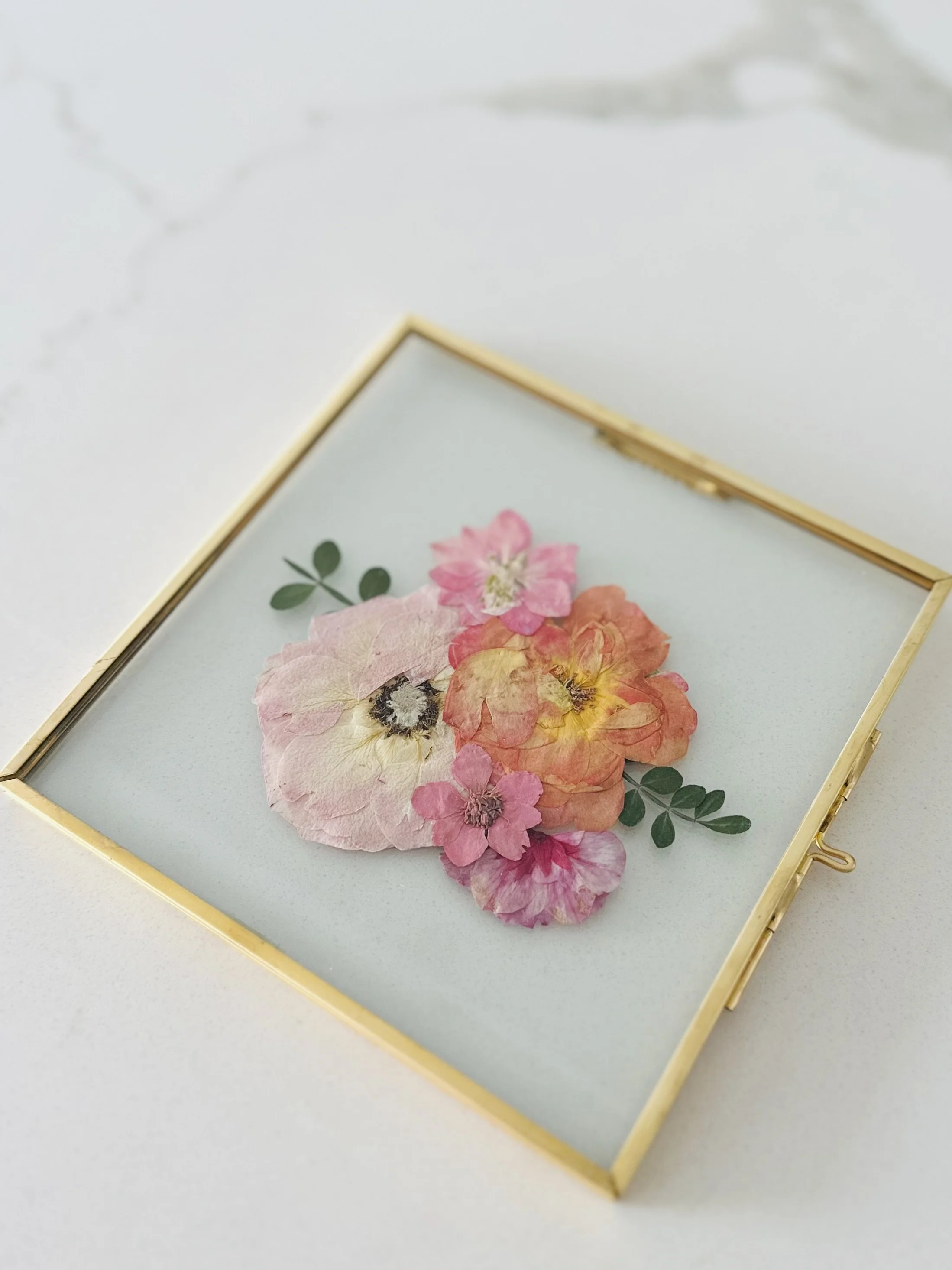 Gold floating frame with pink and orange pressed flowers