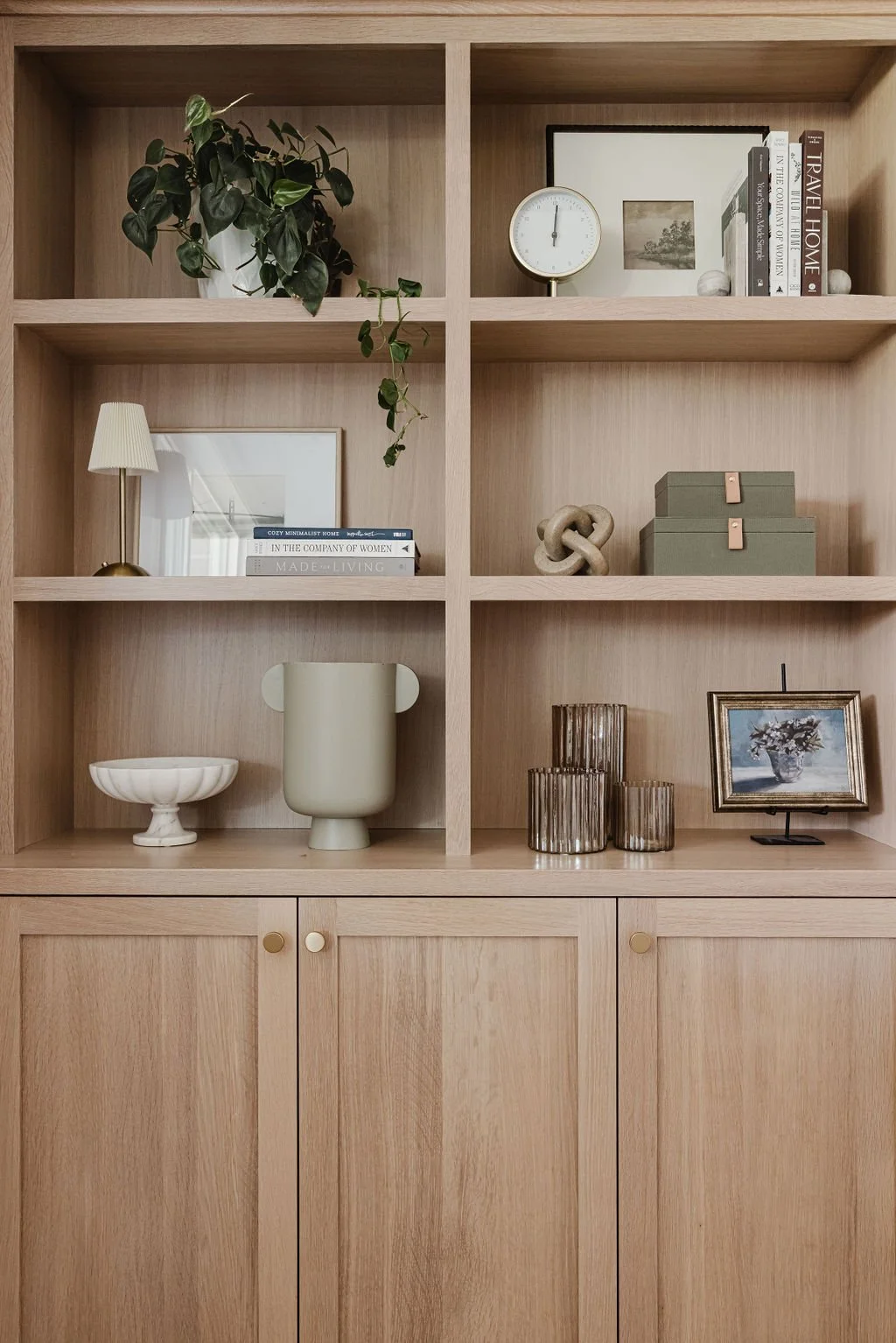 Warm wood built-in shelving unit with curated decor, greenery, and a clean, modern aesthetic.