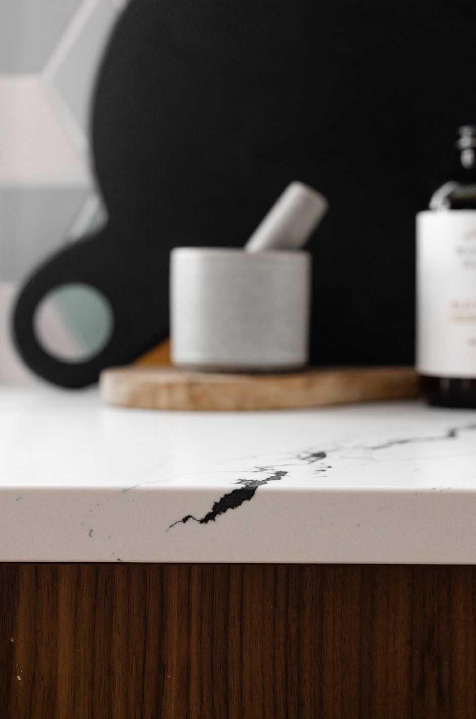 Close-up of white quartz countertop with black veining on walnut kitchen island.