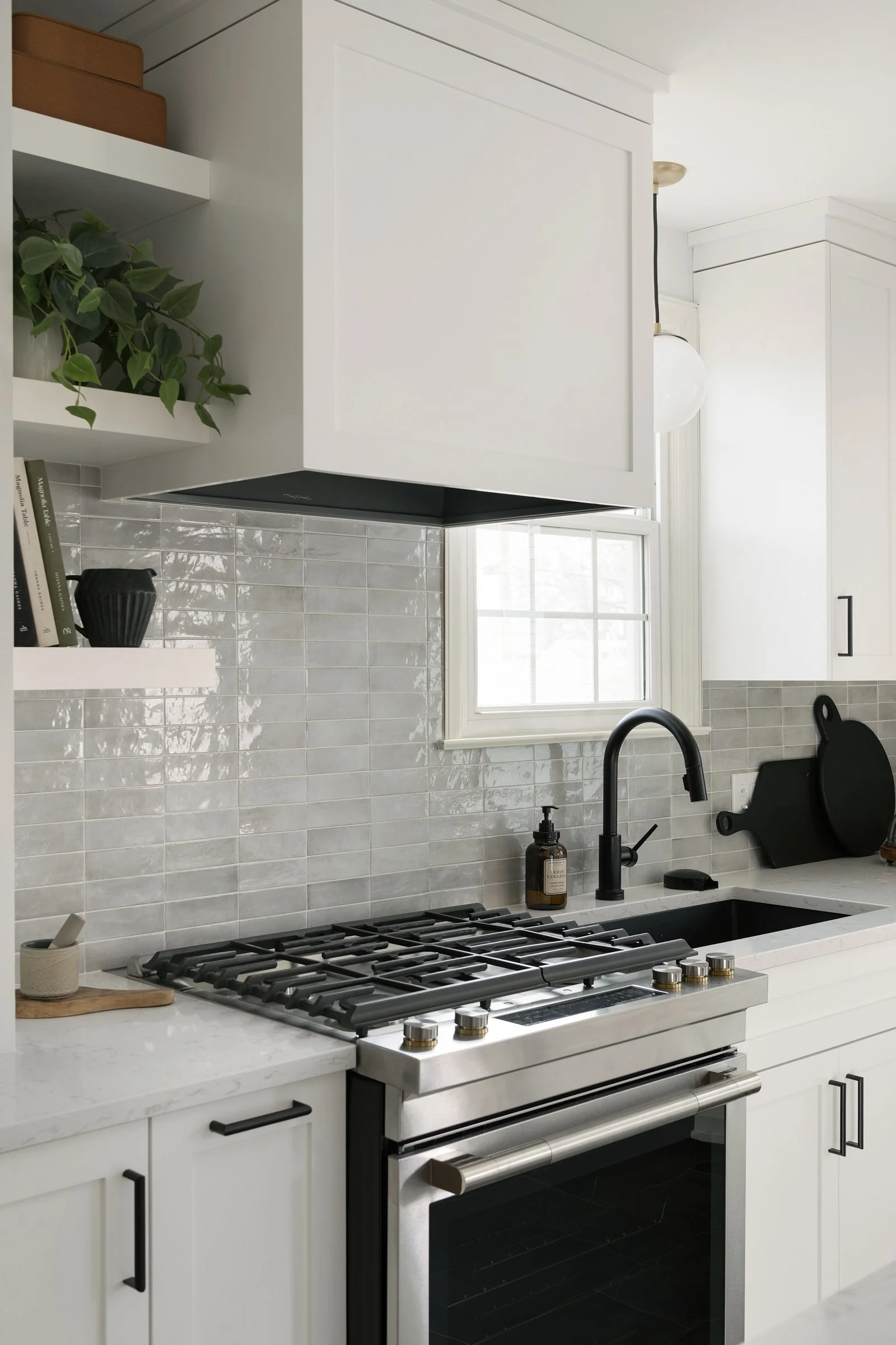 White kitchen cabinets with matte black hardware, an integrated range hood, and a grey tile backsplash.