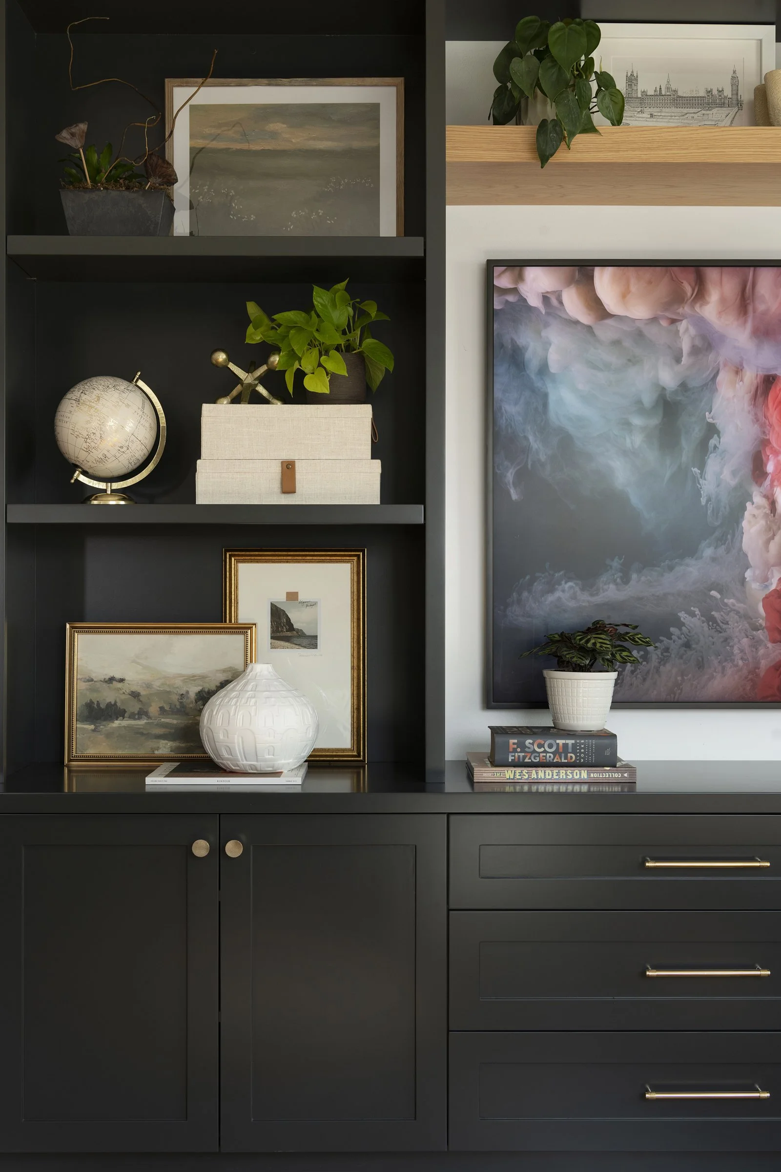 Detailed view of black base cabinets with gold hardware, paired with curated open shelving in a modern living space.
