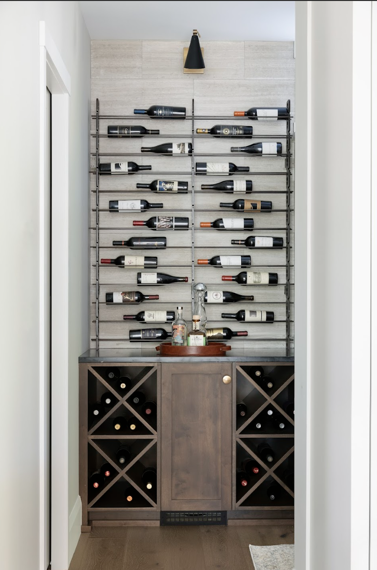 Custom wine cabinet featuring metal wall-mounted bottle racks above stained wood base cabinetry with X-style wine cubbies