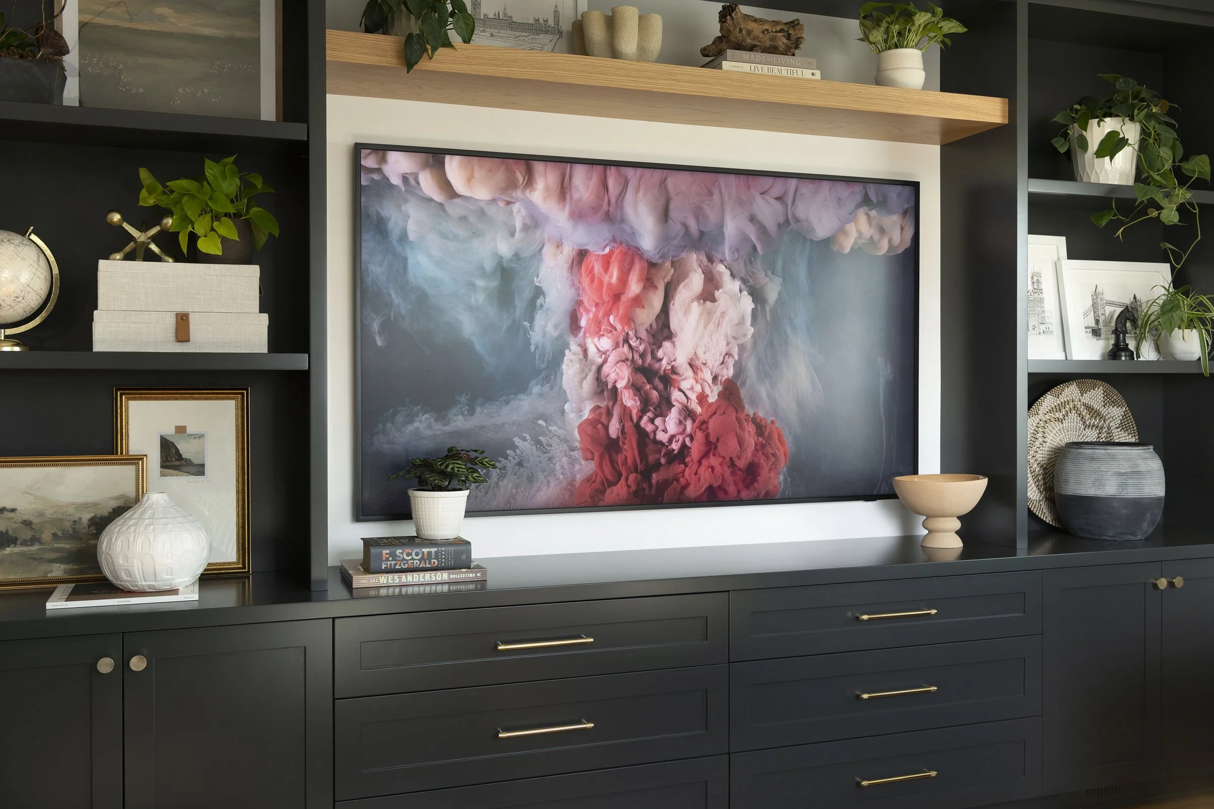 Wide view of custom matte black wall-to-wall cabinets featuring gold hardware, open shelving, and an integrated media center