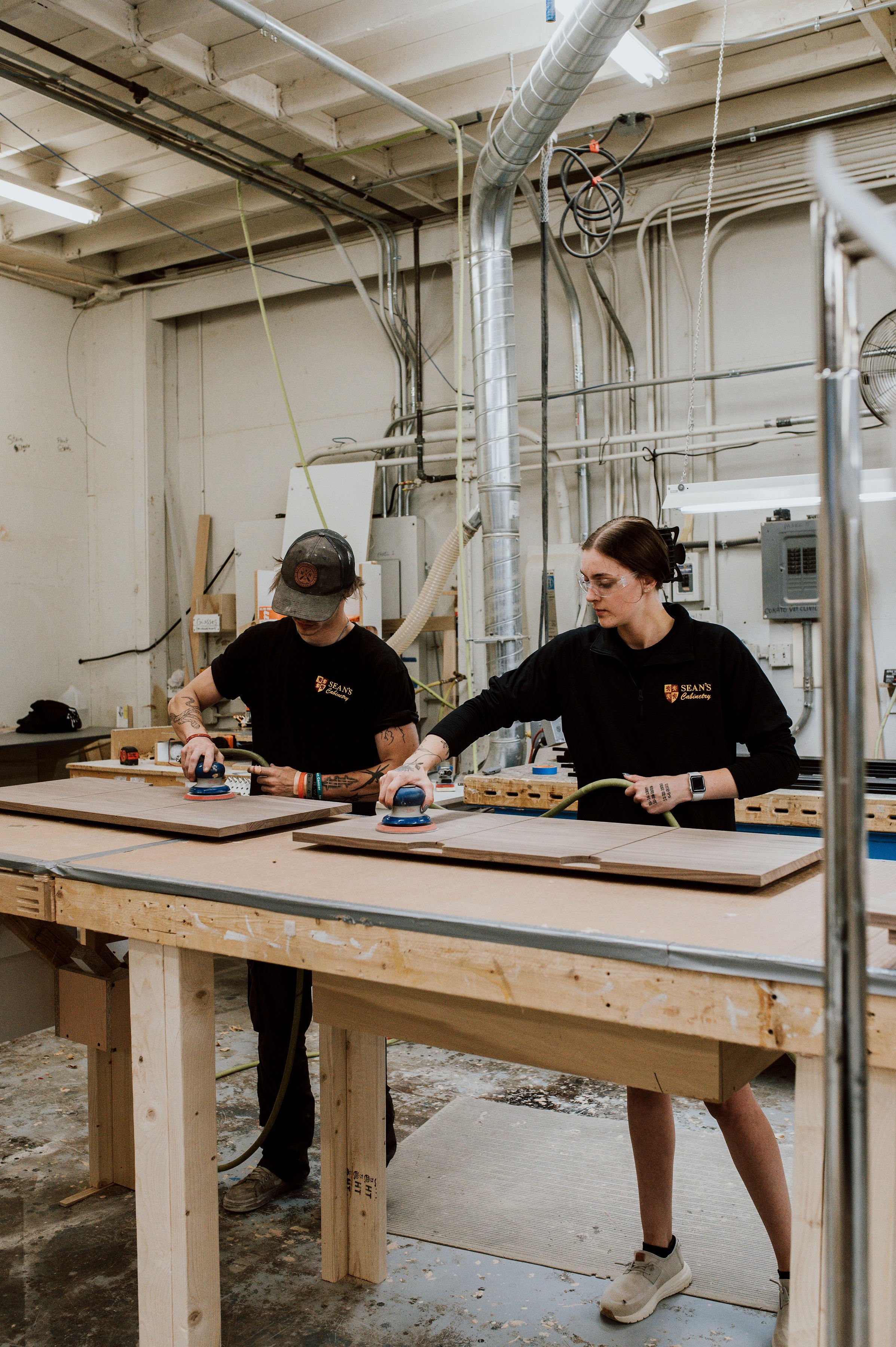 Cabinet shop employees finishing wood cabinet components together