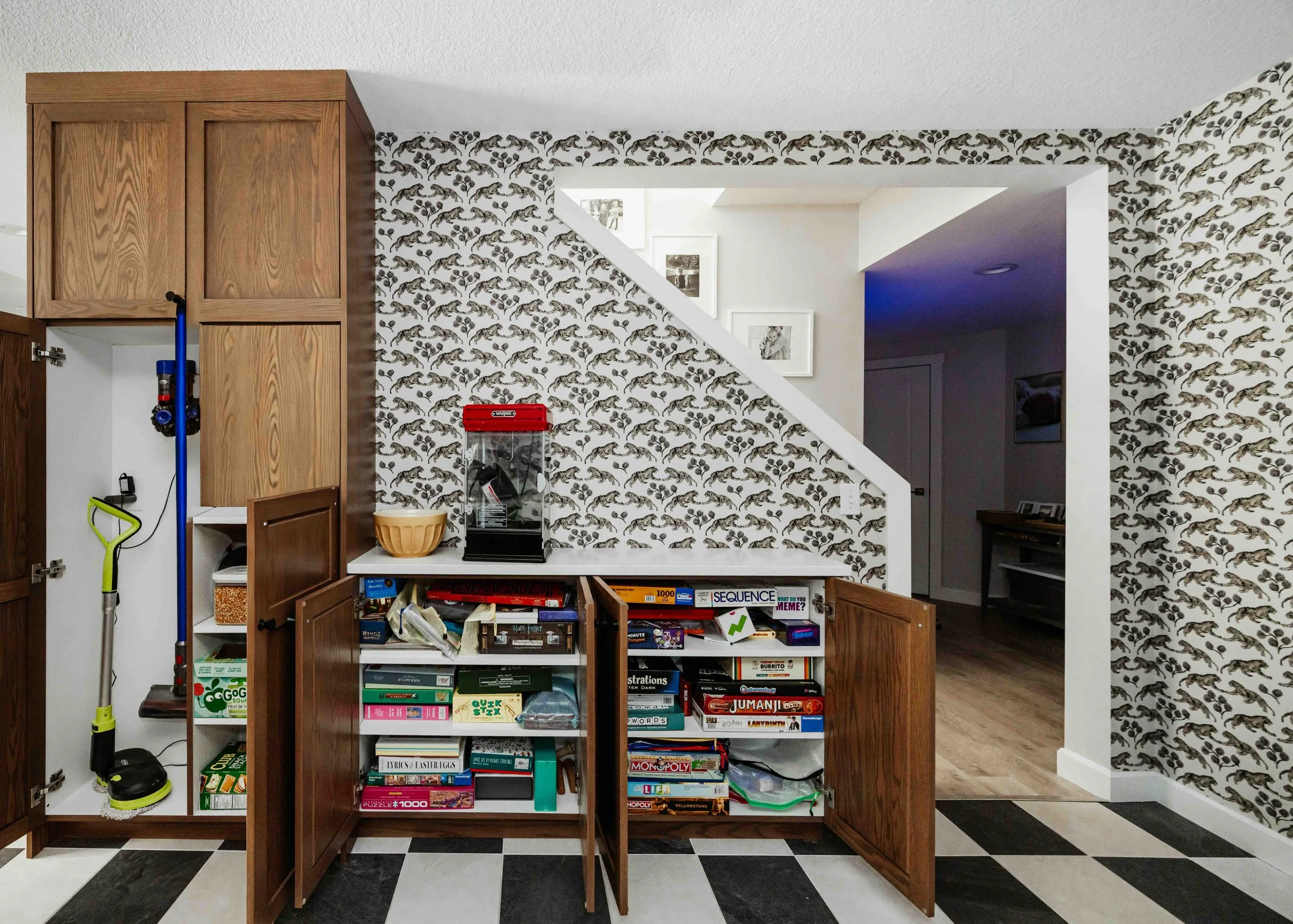 custom frameless red oak cabinetry in a basement; close up photo of cabinetry with open doors ; great storage for vacuum, books, puzzles and board games