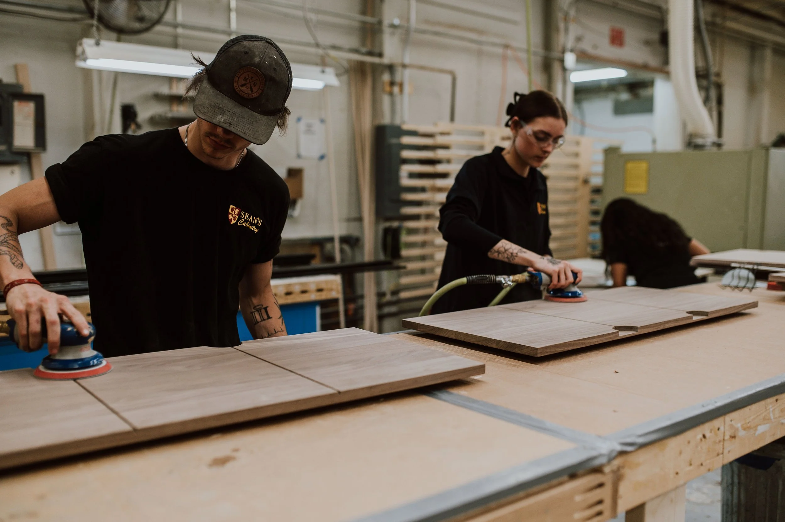 Craftspeople sanding custom cabinets in production workspace