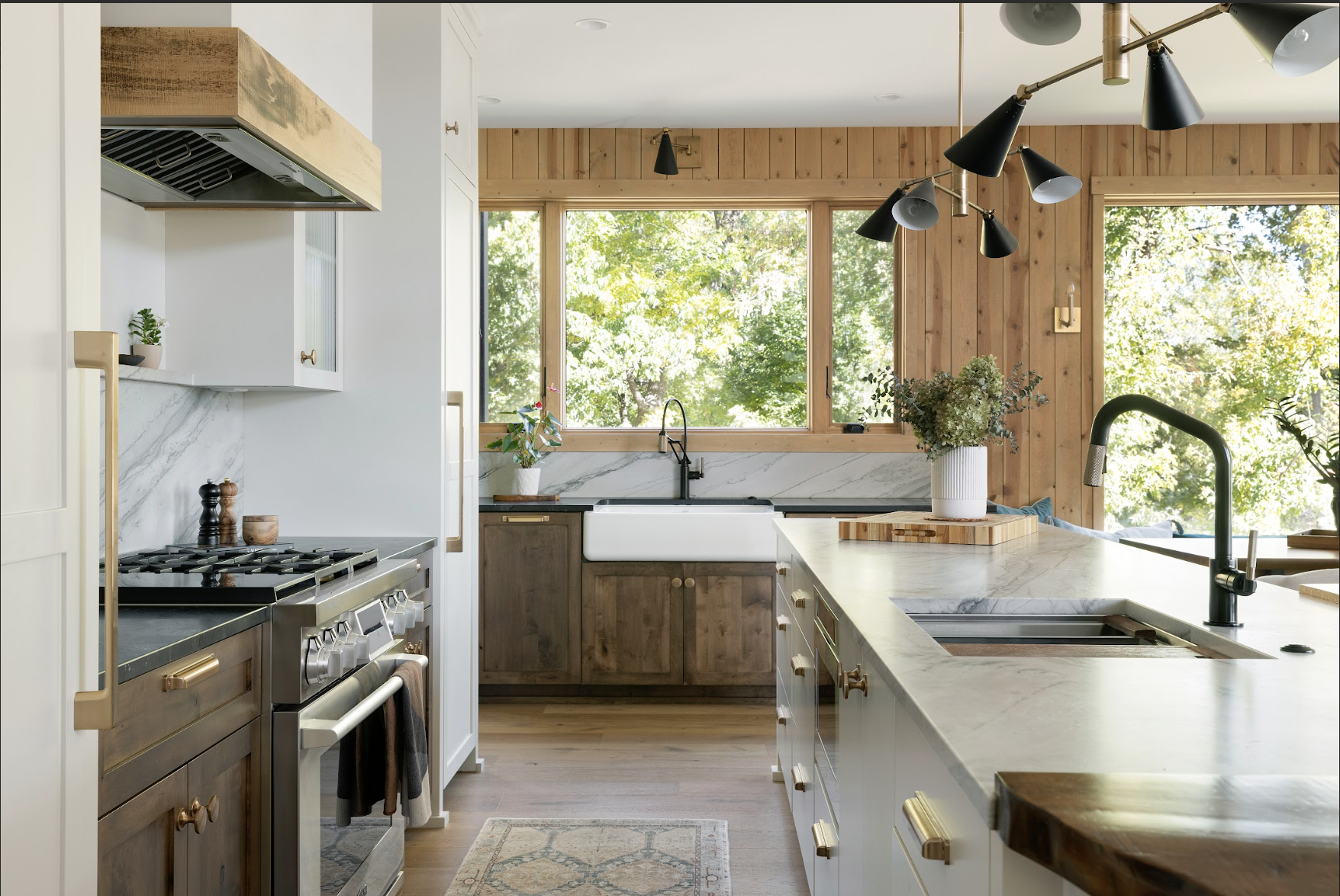Custom kitchen cabinetry featuring stained wood base cabinets, a white island with cabinetry, and brass hardware