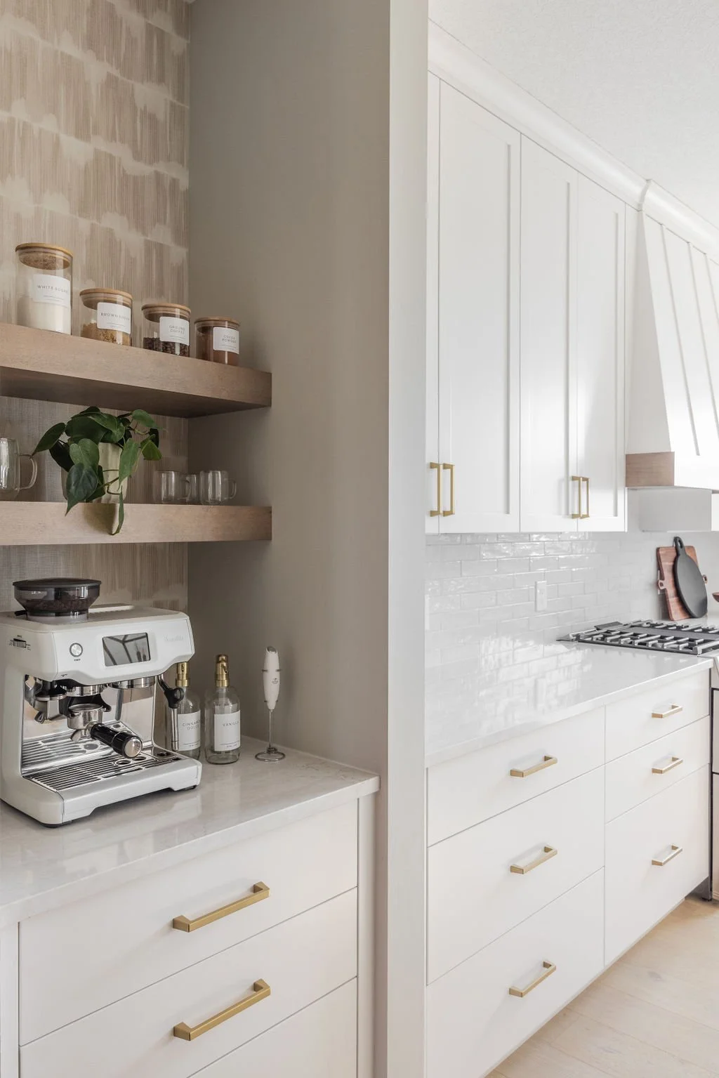 Custom kitchen cabinets with gold hardware, quartz countertops, and a coffee bar featuring floating wood shelves and organized storage jars.
