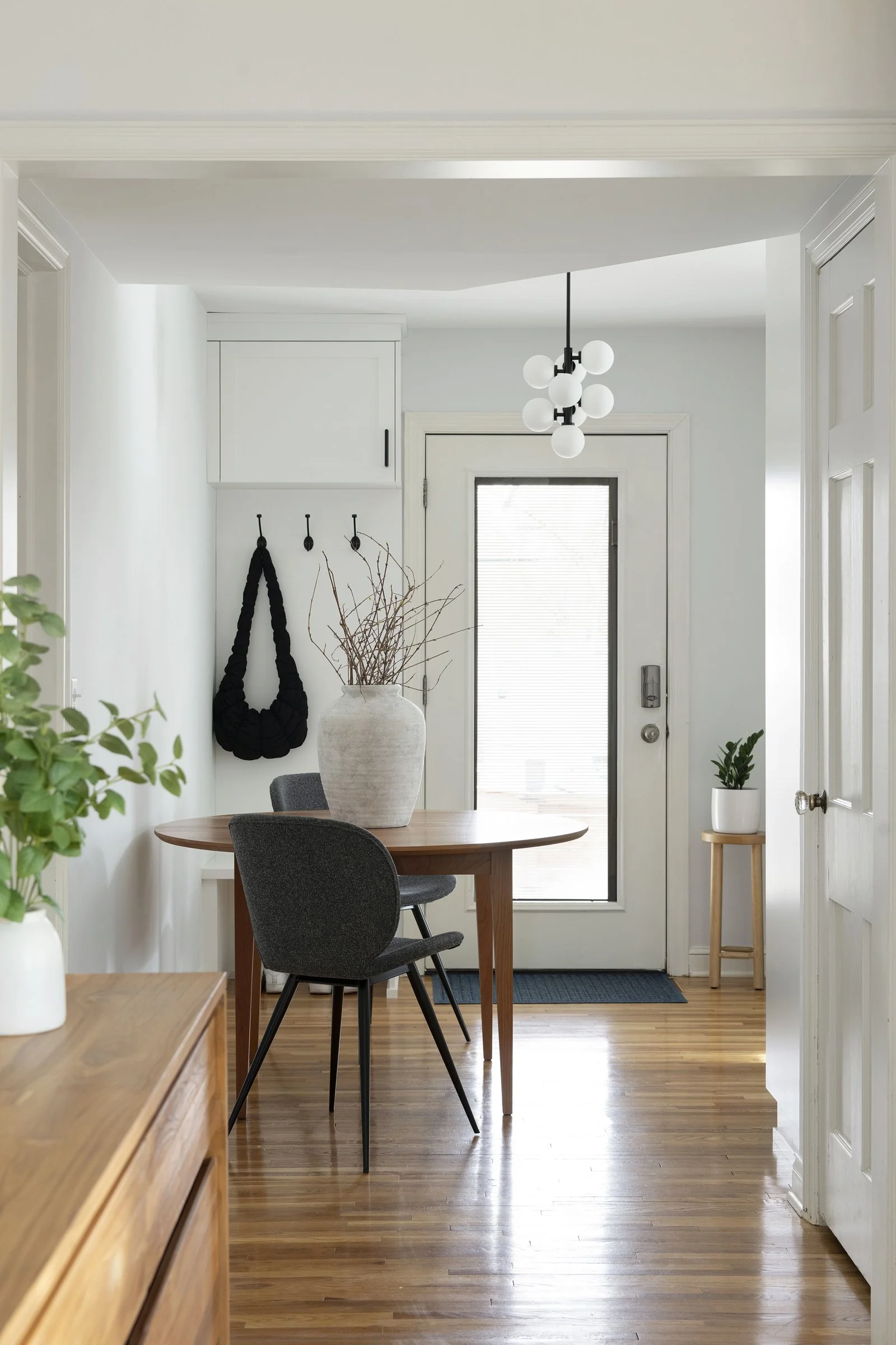 Dark built-in cabinets with open shelving in a modern hallway. A green plant sits on a cabinet