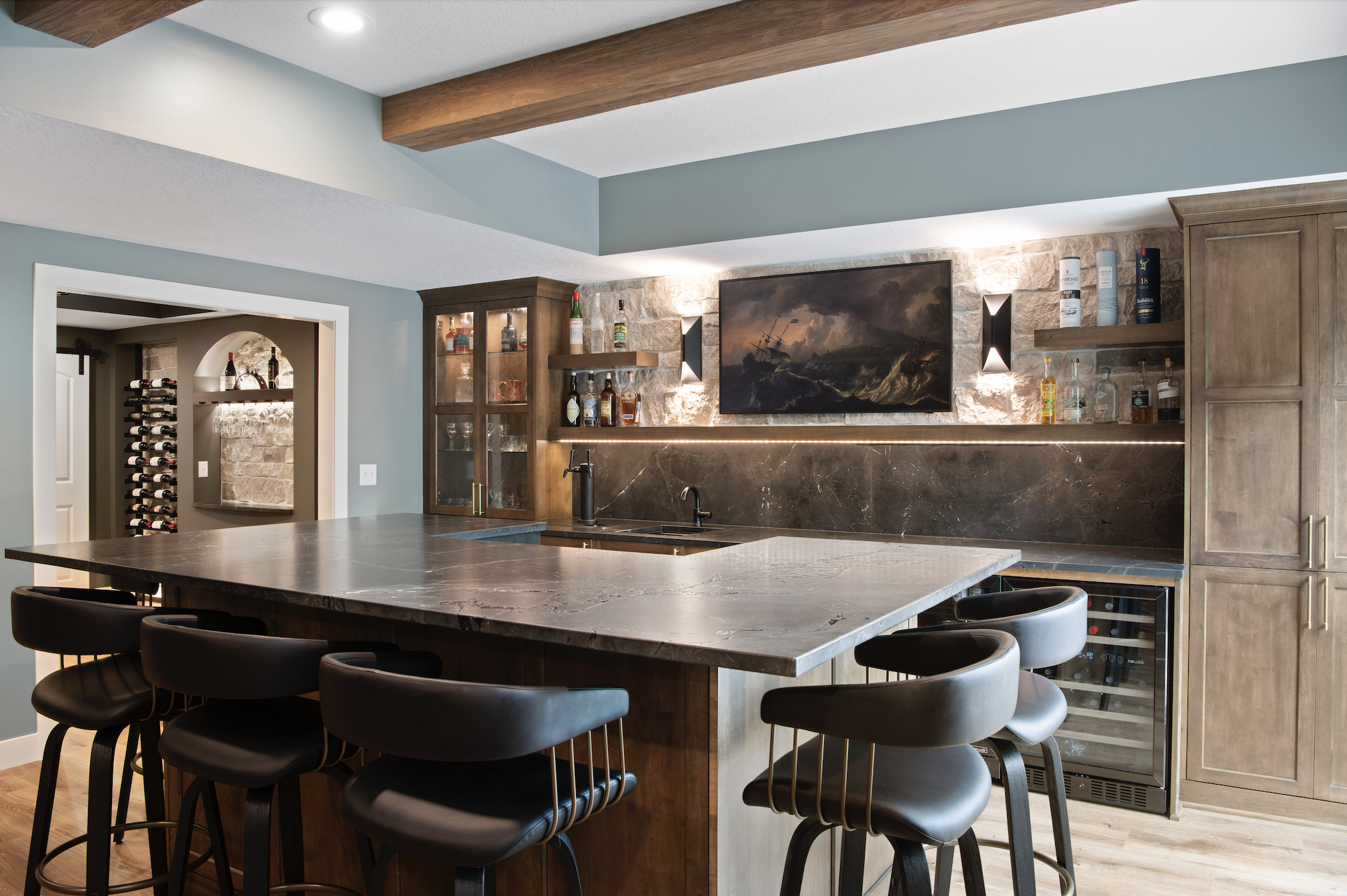 Custom cabinetry and built-in home bar featuring warm wood cabinets, stone countertops, floating shelves, and a large island with bar seating.