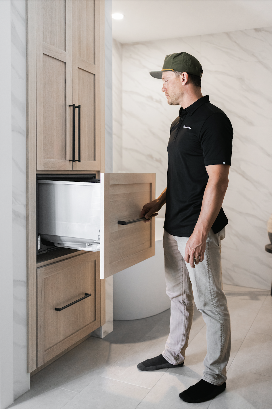 Man opening pull-out storage inside tall light wood bathroom cabinets