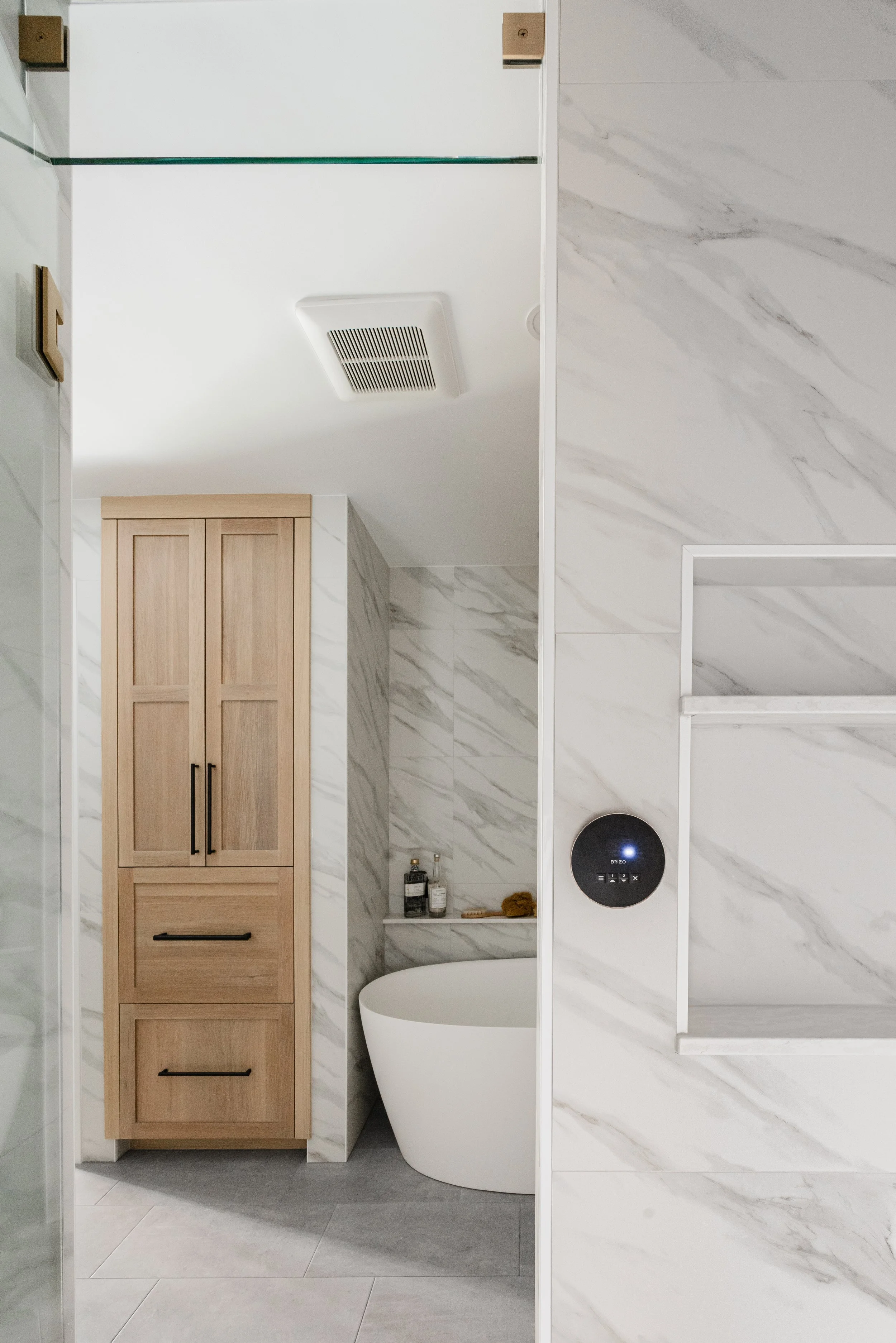 Light wood bathroom cabinets next to freestanding tub in modern space