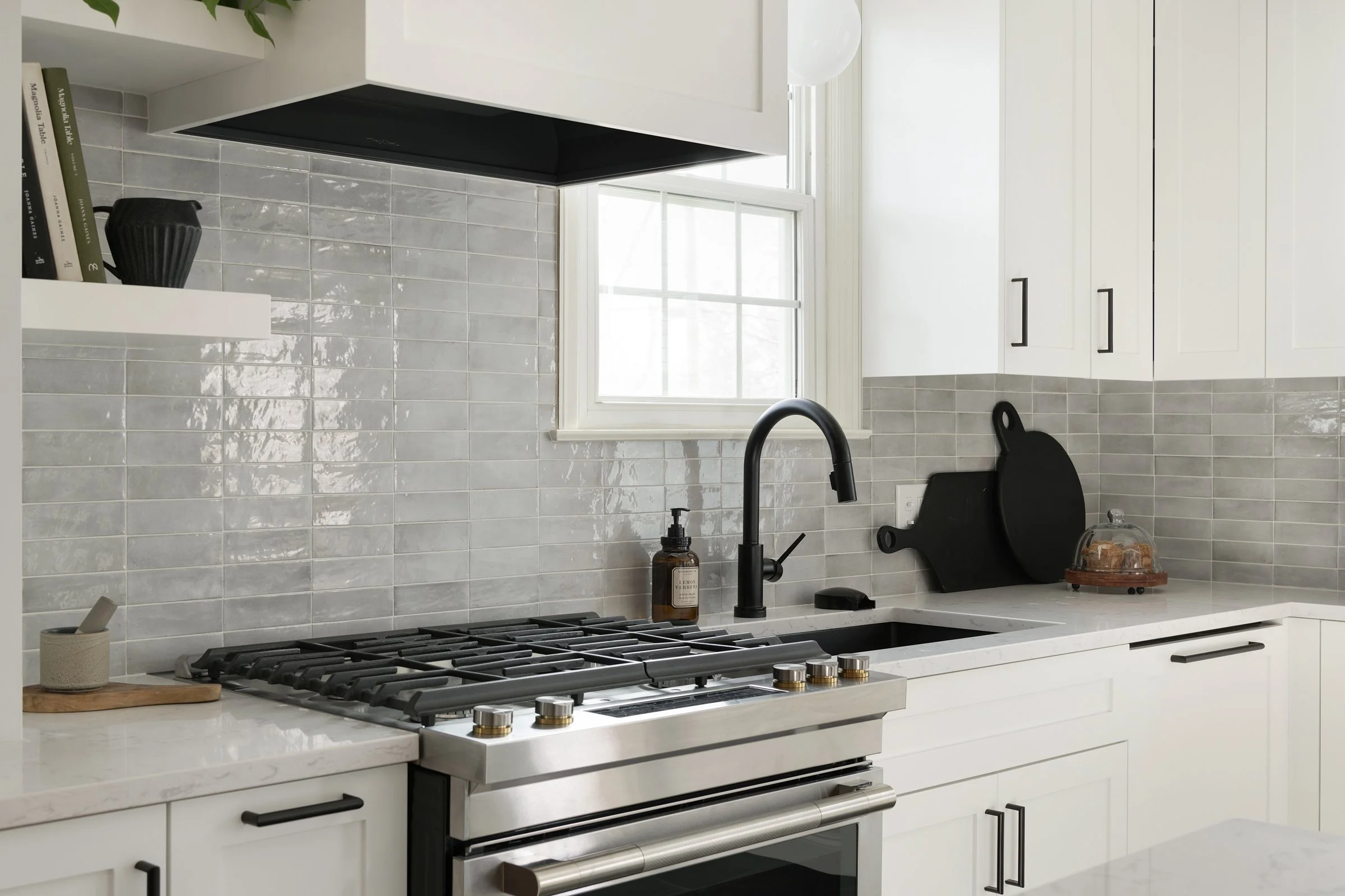 Bright kitchen with white shaker cabinets, gray tile backsplash, and stainless range
