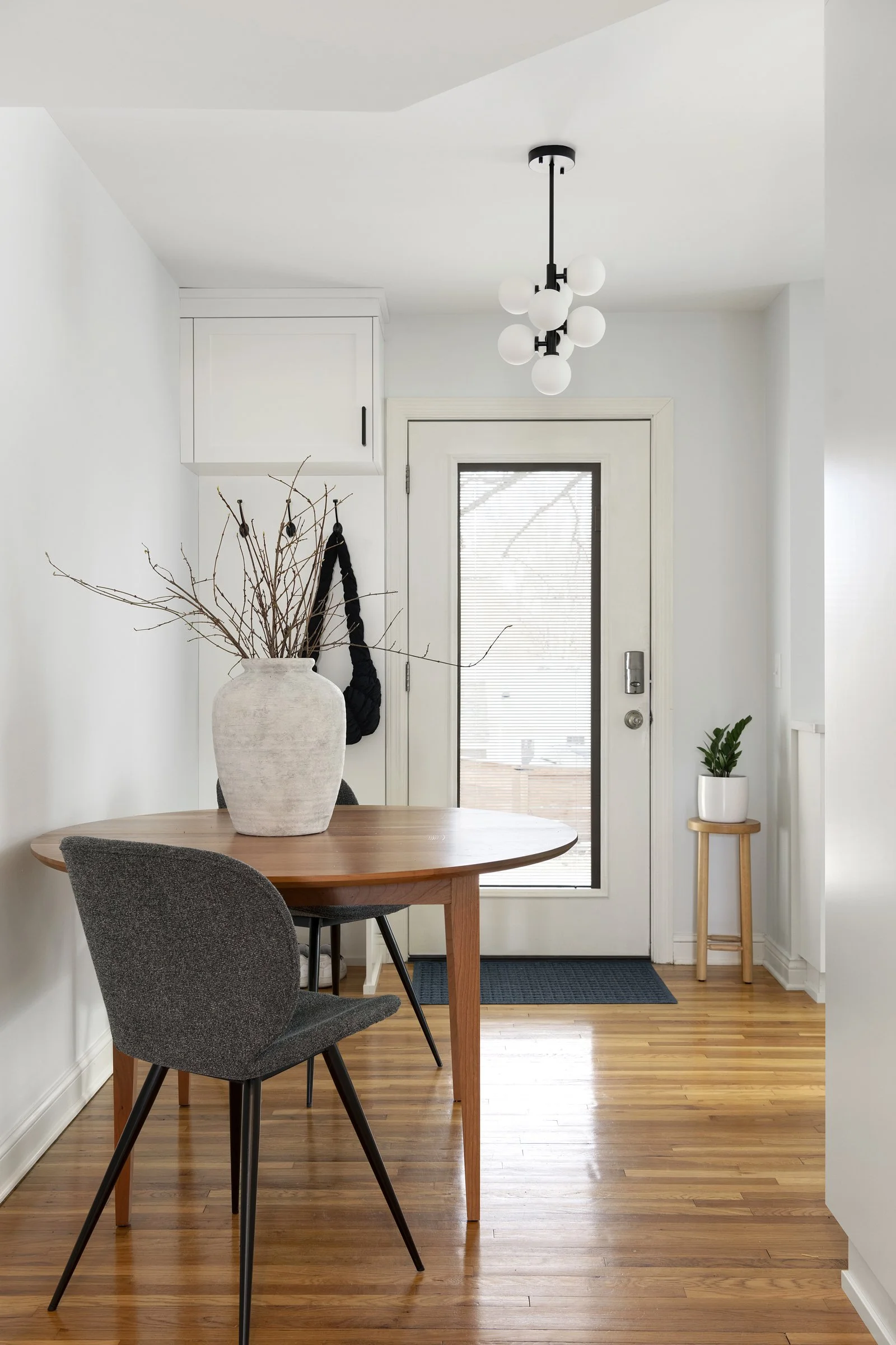 Minimalist white wall-mounted storage cabinets installed in a dining and entryway area.