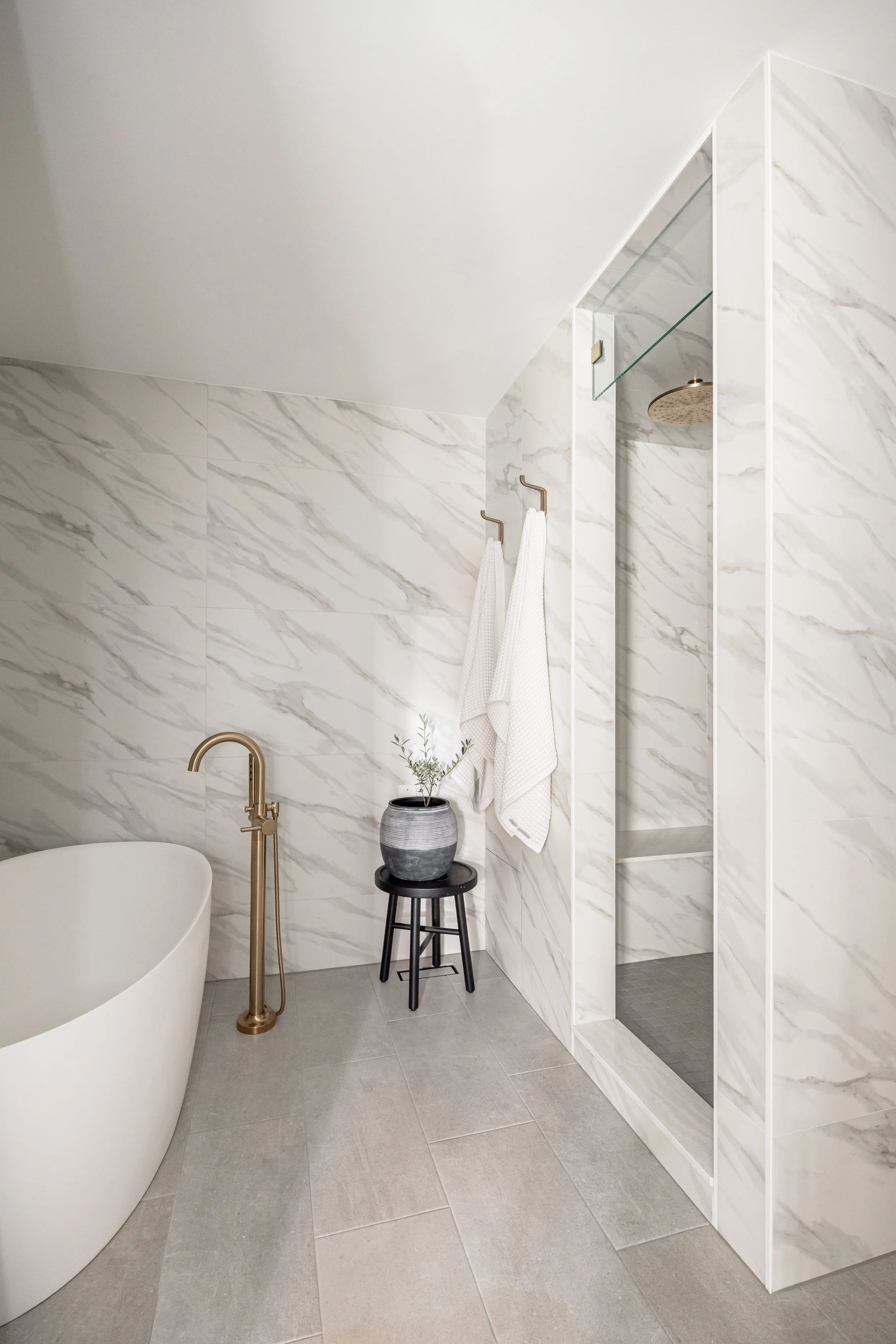 Modern bathroom with marble tile shower and light wood cabinets in spa-style layout